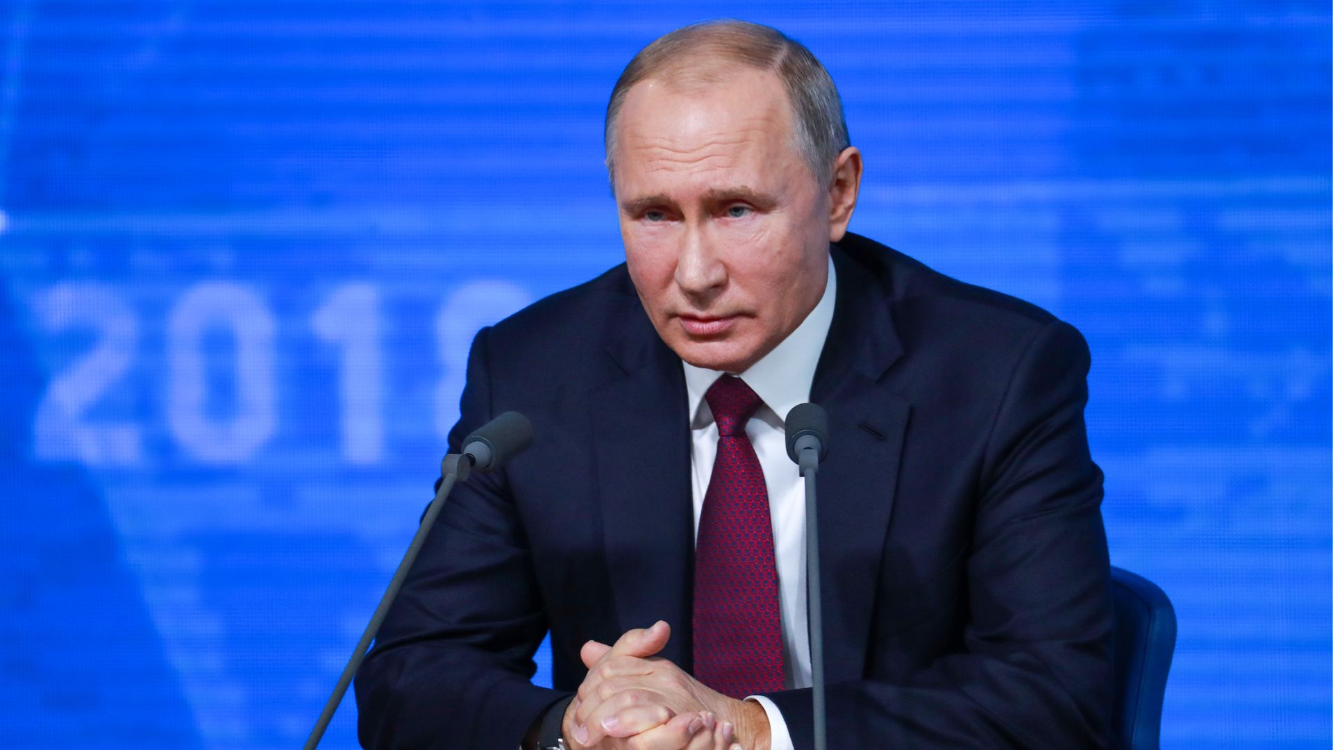 Vladimir Putin sitting at a news conference in russia