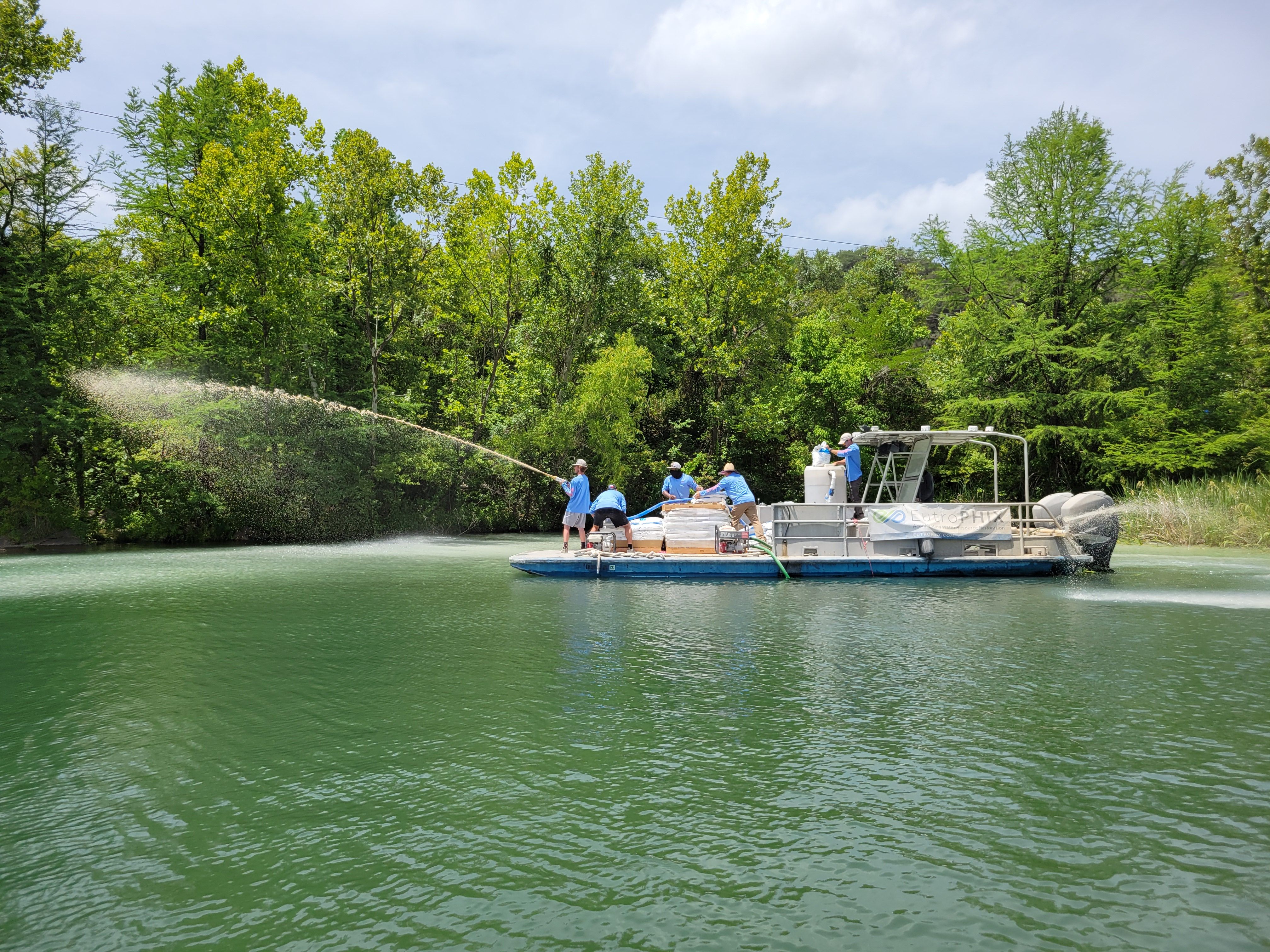 A photo of workers spraying clay on the water.