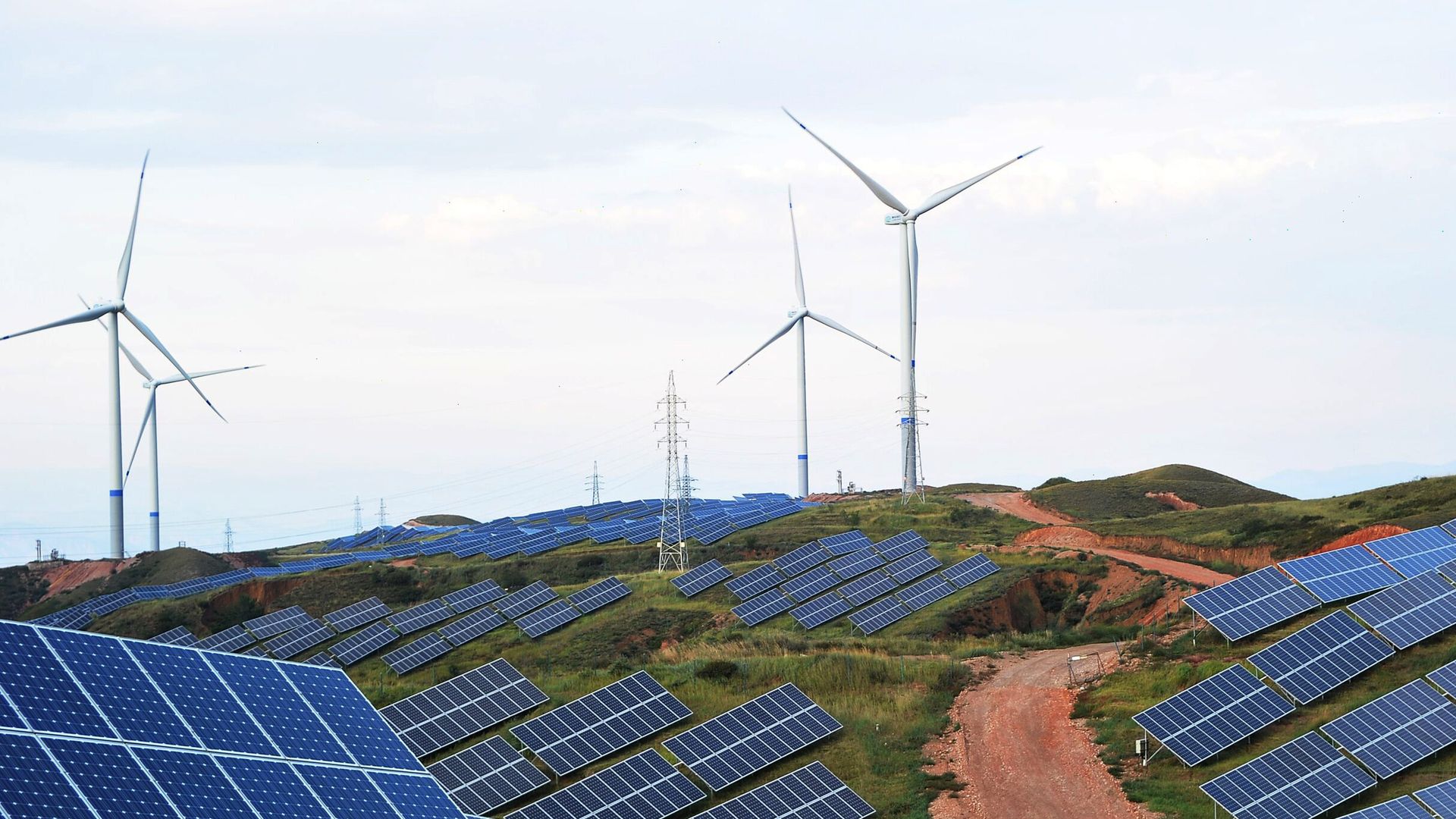 Solar panels and wind turbines are pictured on a barren mountain at Shenjing Village on July 2, 2018 in Zhangjiakou, Hebei Province of China