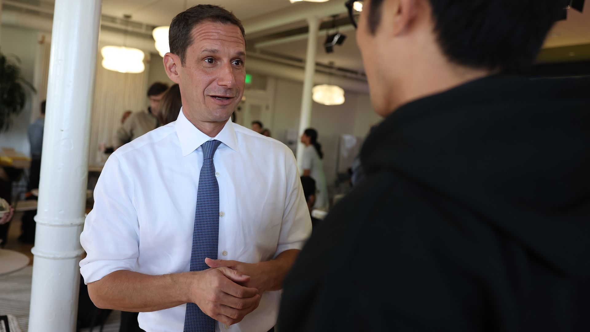 Photo of Daniel Lurie speaking with someone at an event