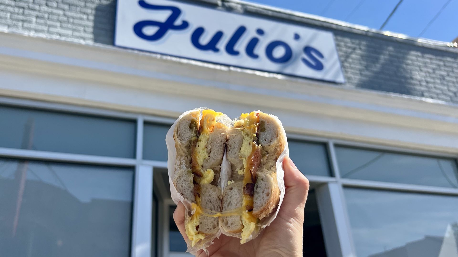 a pic of a bagel in the air in front of a building that says "julio's" in blue letters