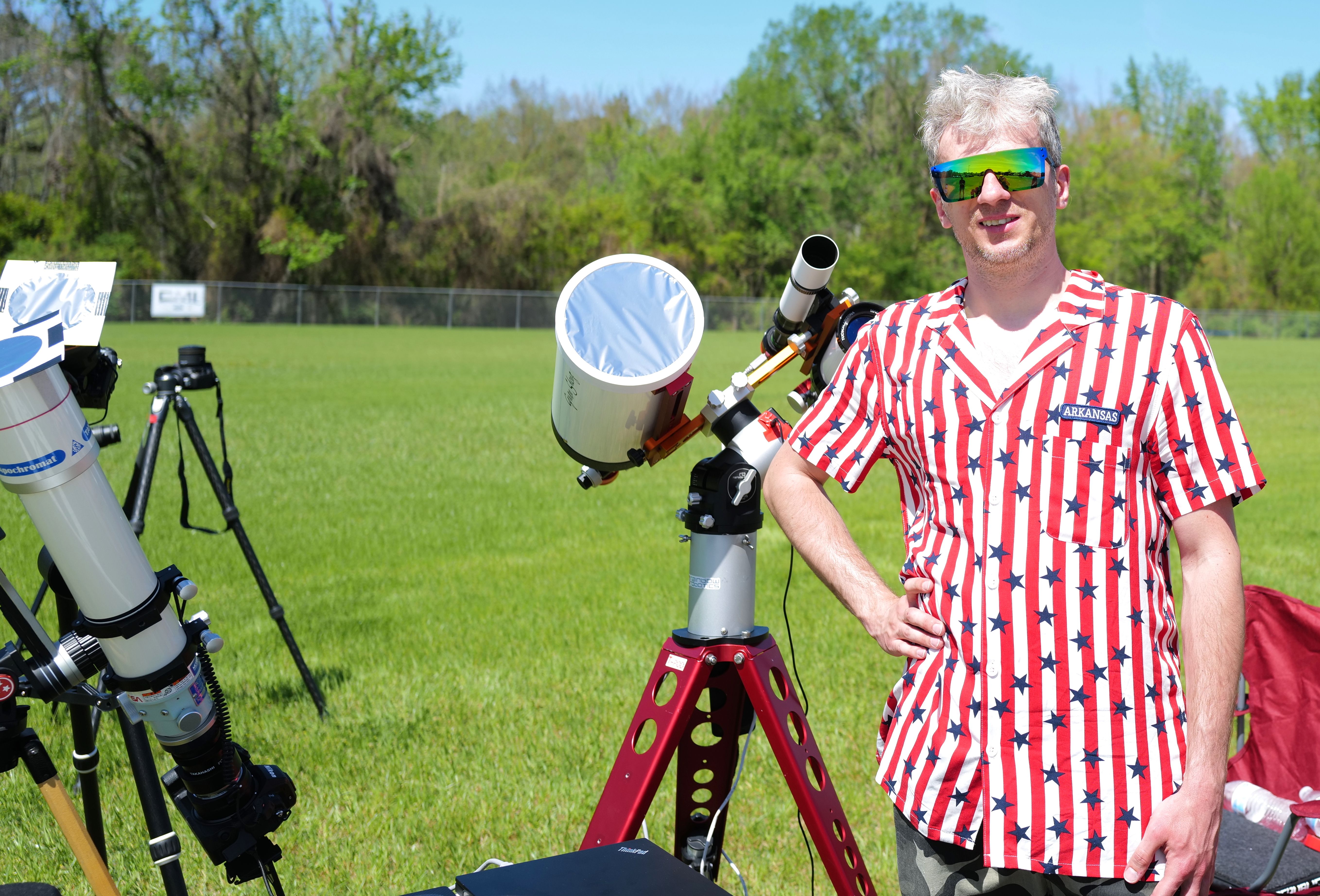 A man stands next to his telescope.