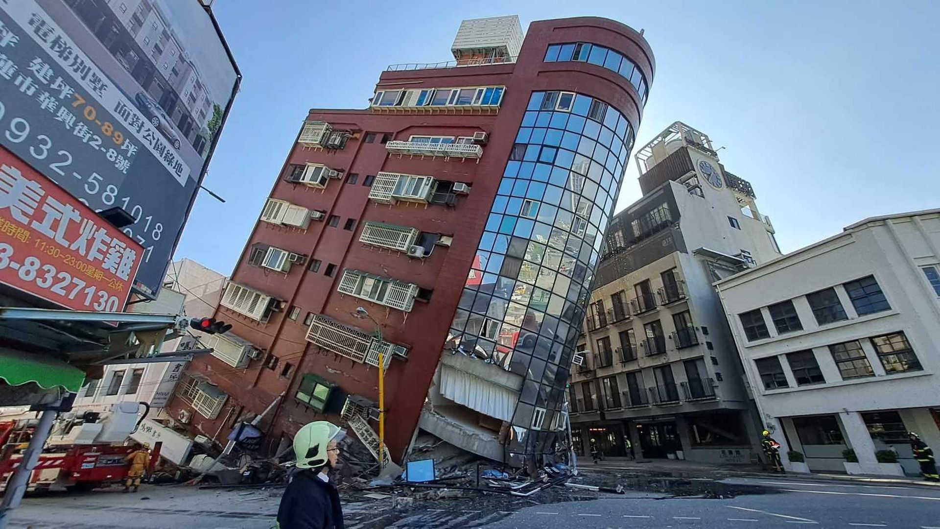 A building leans precariously with rubble underneath.