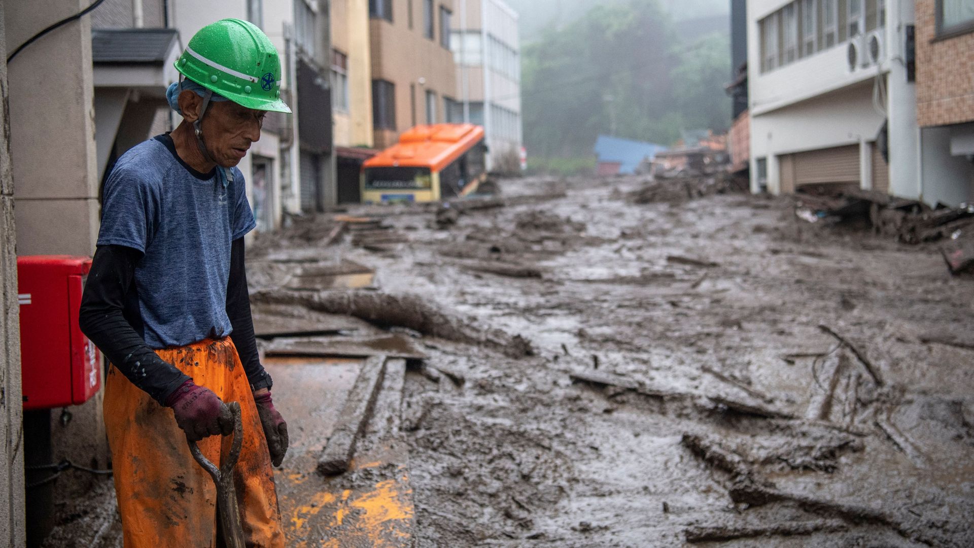 Picture of a rescue worker standing while looking at the scene of a mudslide