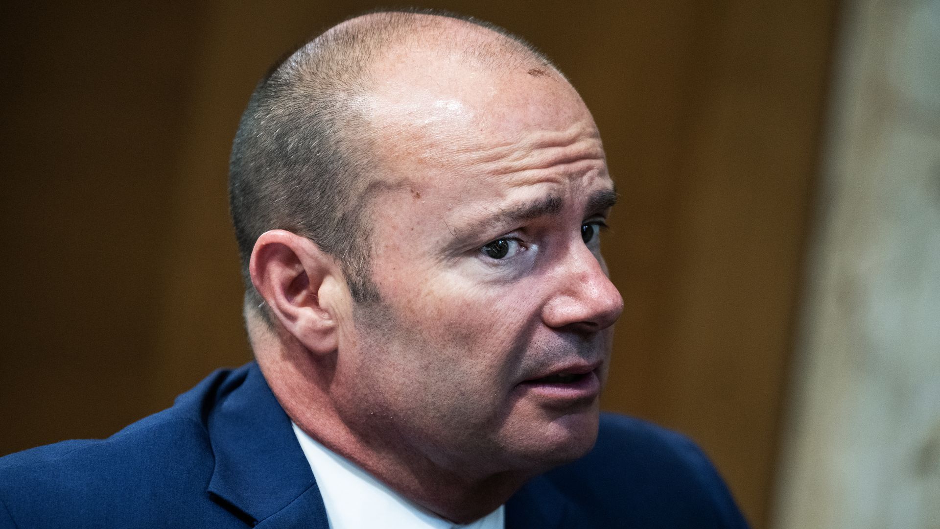 Mike Lee looks to his right while speaking in a blue suit. 