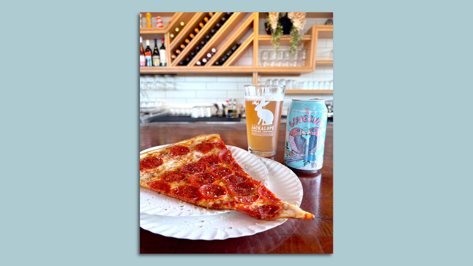 A piece of pizza next to a can of craft beer.