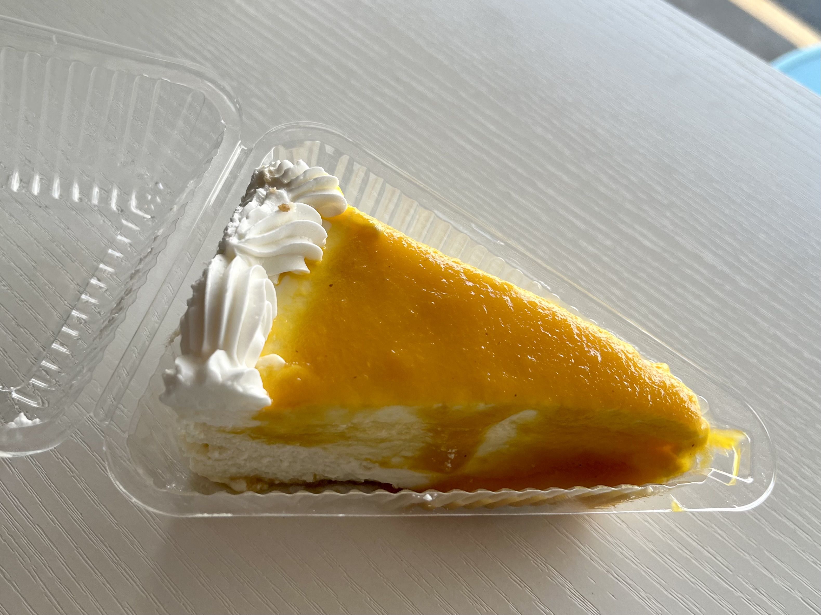 A slice of cheesecake, topped with a glossy orange glaze.