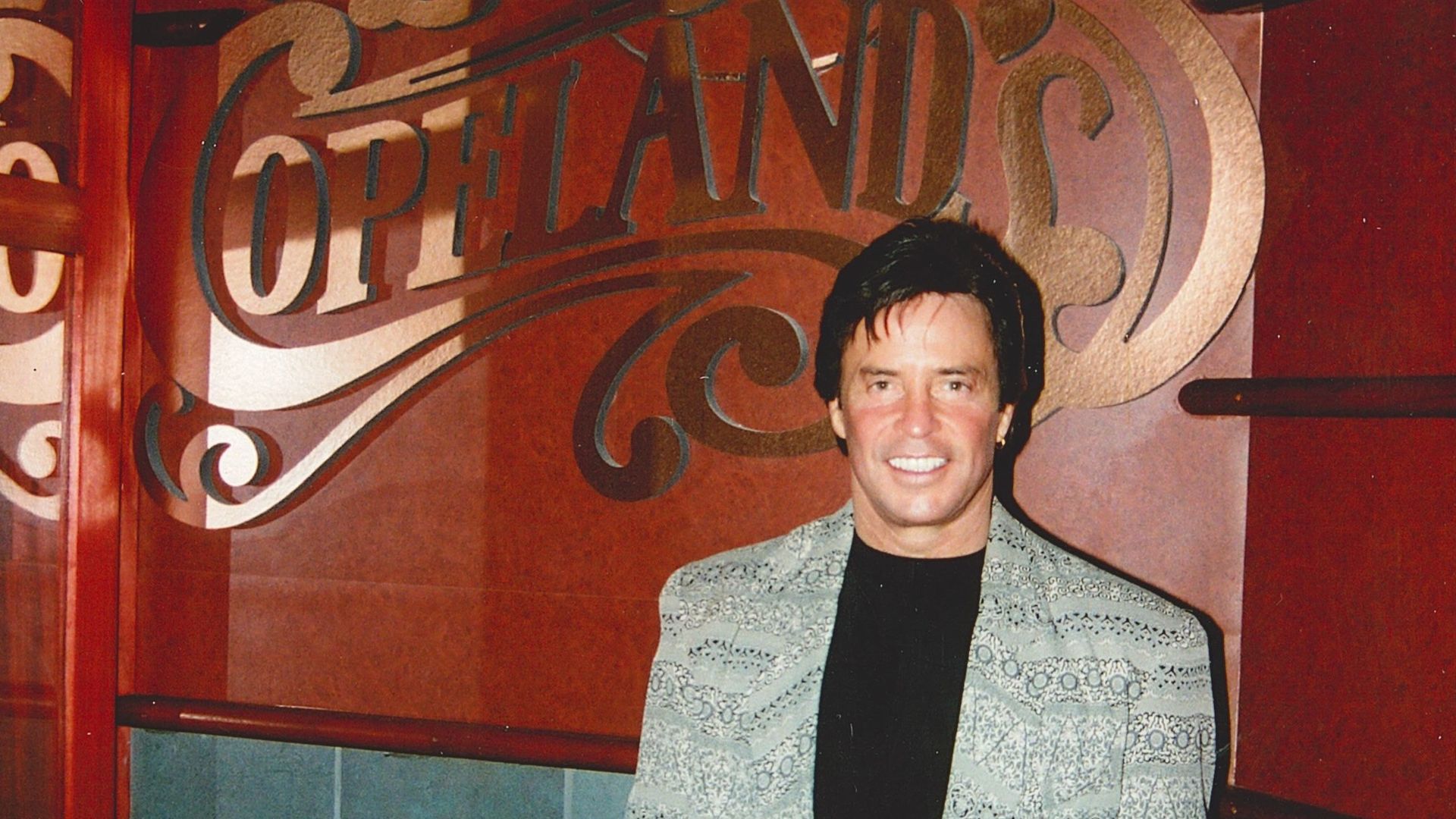 Photo shows Al Copeland in front of the Copeland's sign