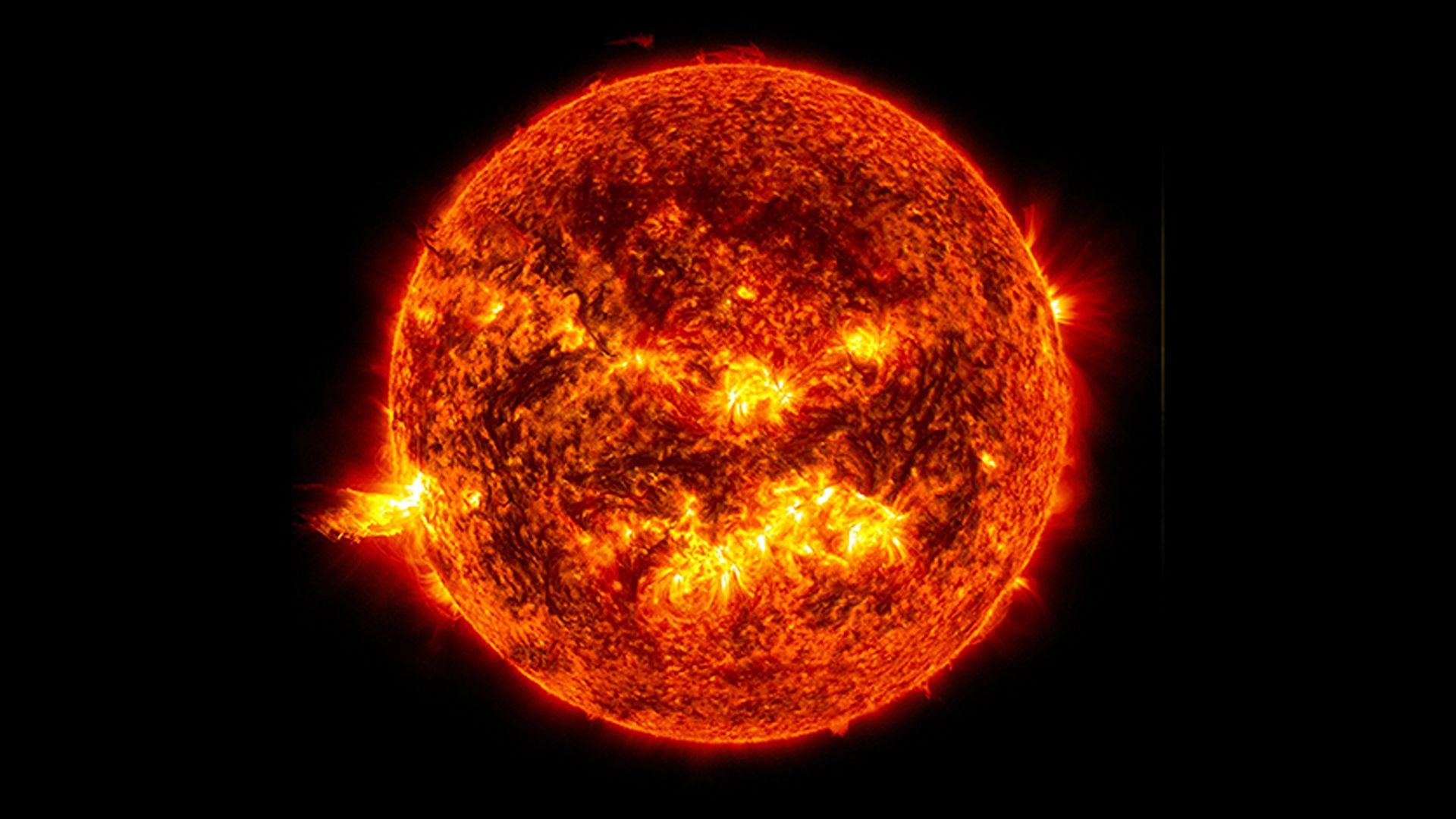 A yellow solar flare on the left side of the orange sun.