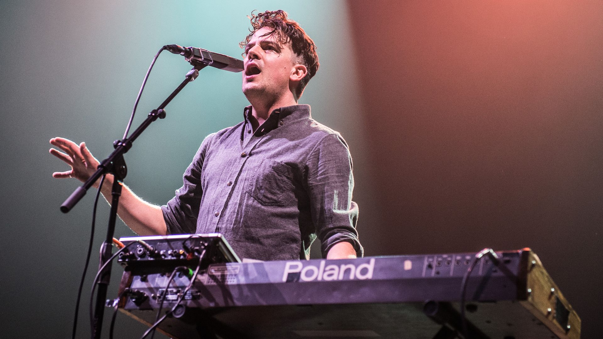 Photo of a man singing and playing keyboard in a concert