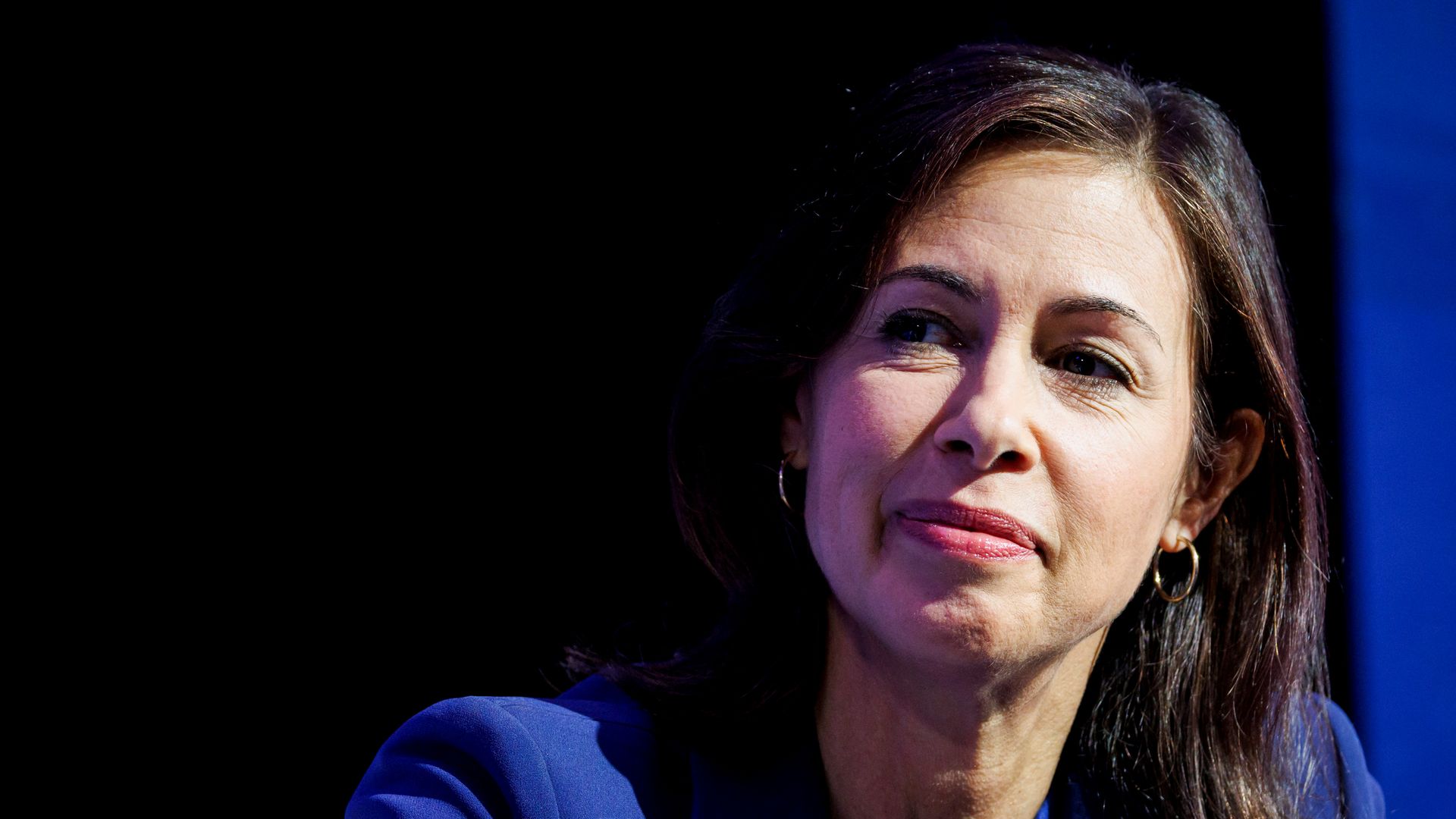 A person in a blue suit looks to the side