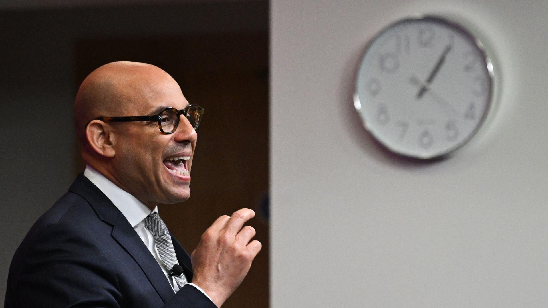 United Nations' top climate official Simon Stiell speaking next to a clock mounted on a wall.