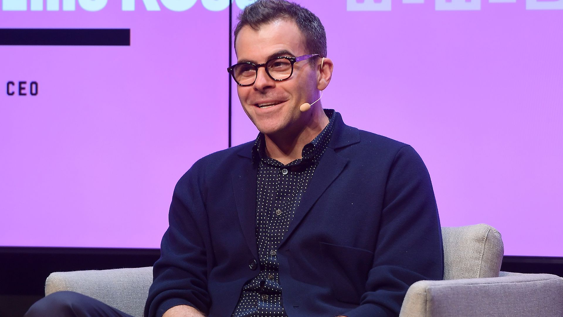 Photo of Adam Mosseri wearing glasses on stage with his hands folded in his lap