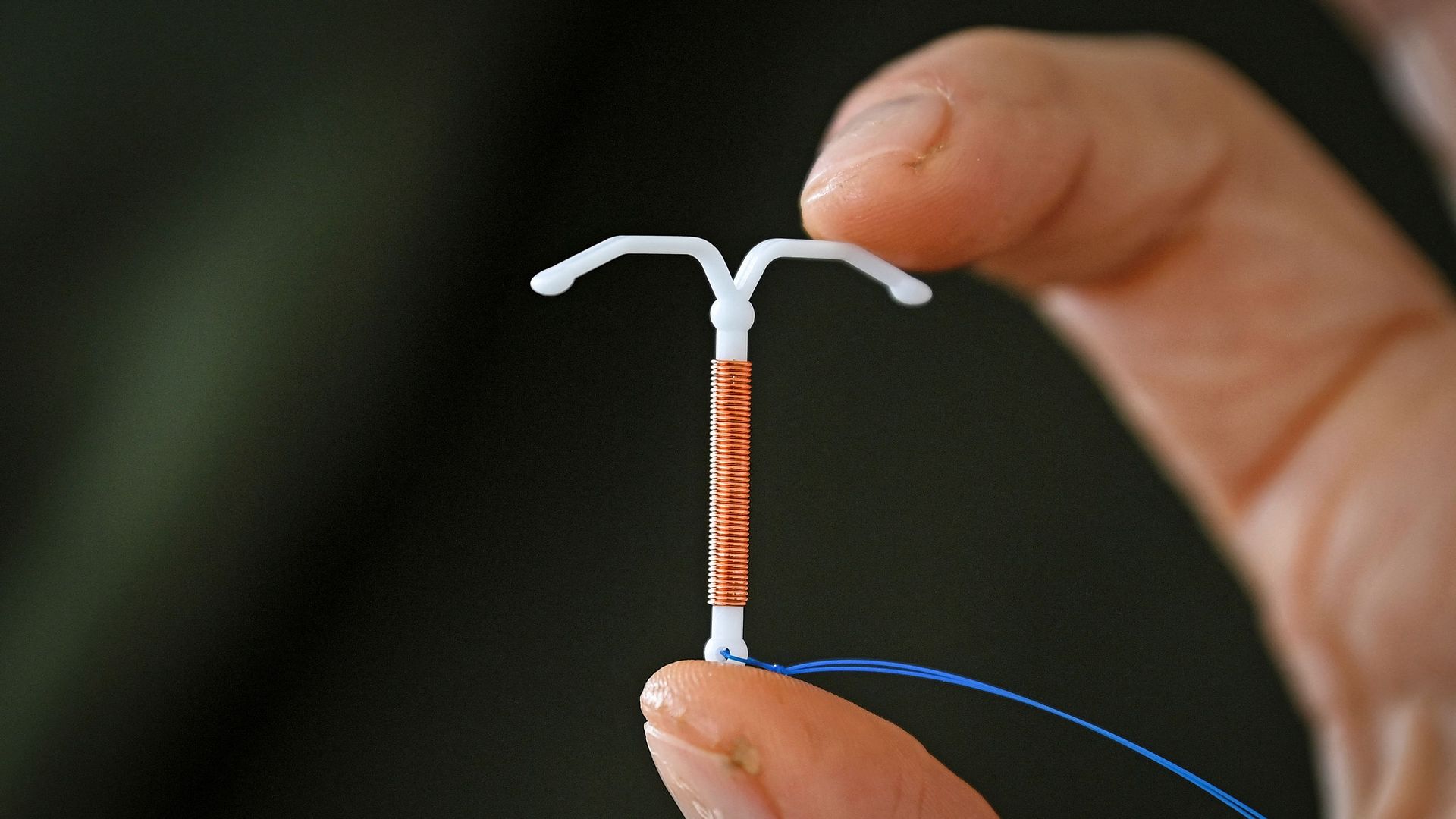 Fingers holding up an IUD