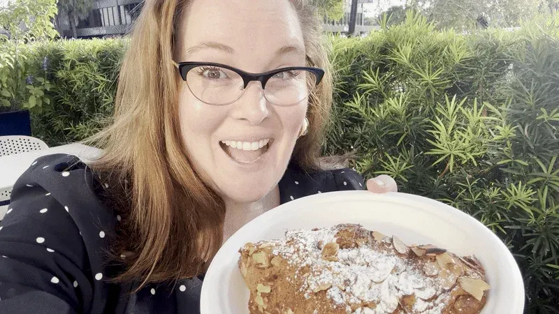Image shows Carlie smiling with an almond croissant.