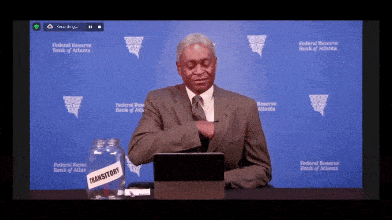 Raphael Bostic drops a dollar bill in a jar