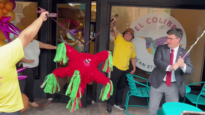 Pittsburgh Mayor Corey O'Connor whacks a red and green piñata in front of El Colibri restaurant in Garfield.