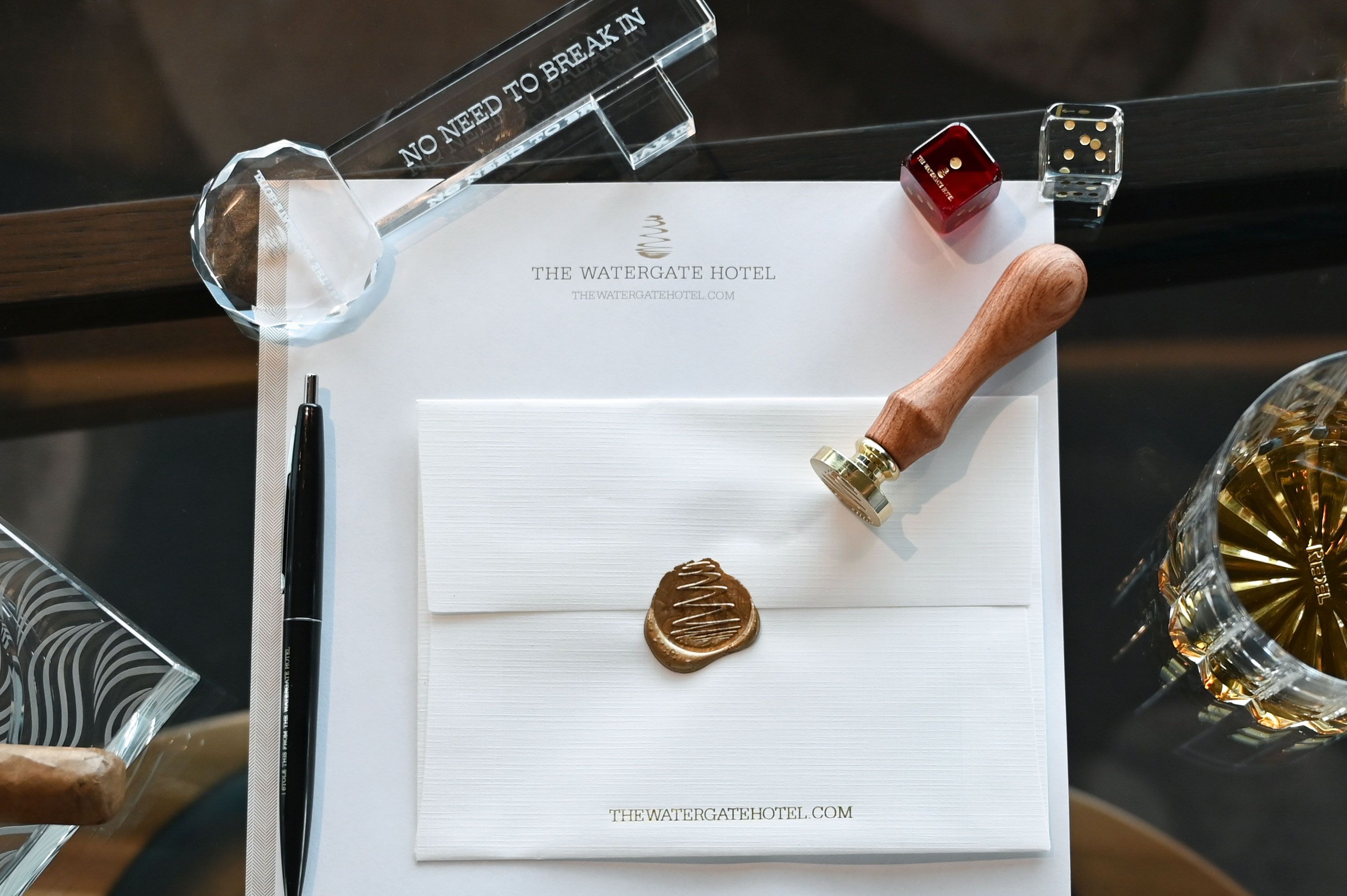 A desk at The Watergate with an envelope and seal, and a glass key reading "No need to break in"