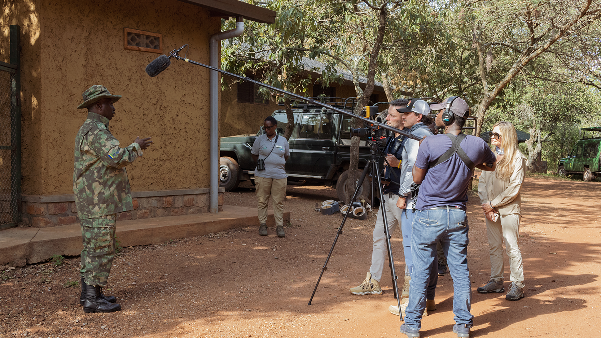 A group of people stand behind a boom microphone and camera while a man is being interviewed.