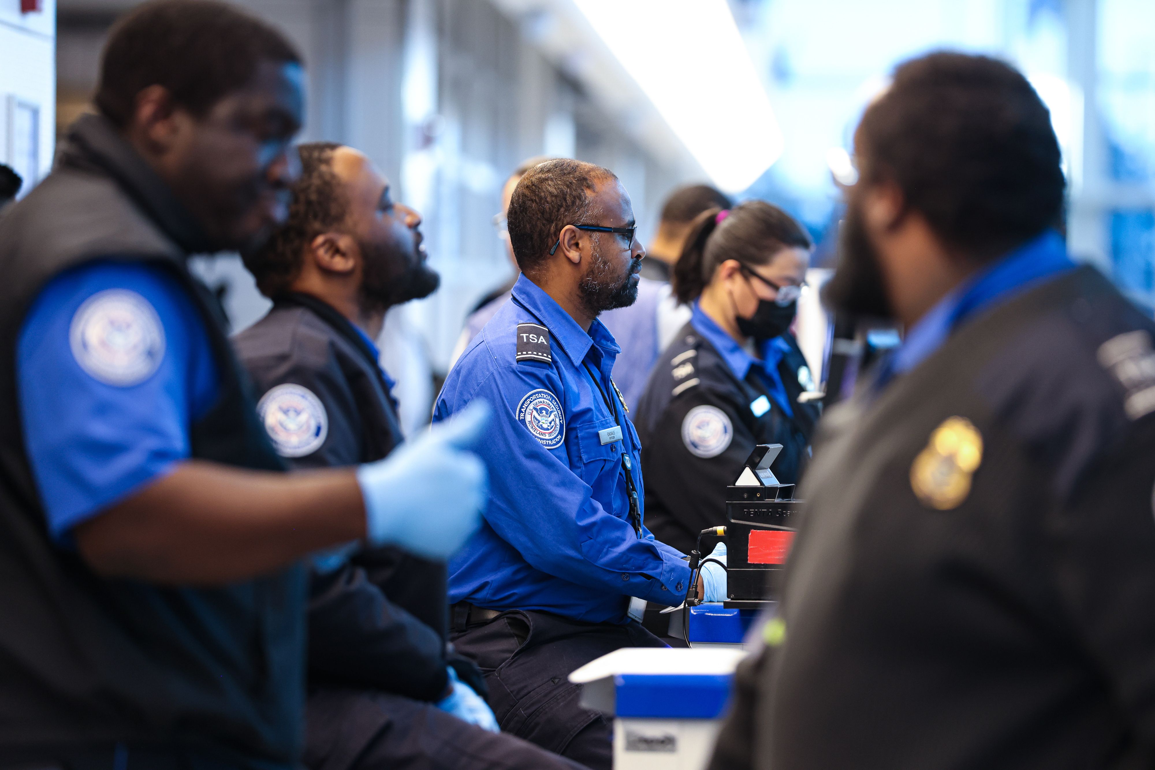 TSA agents conduct passenger screening at Reagan National Airport as travelers move through security lines following major winter storm disruptions.