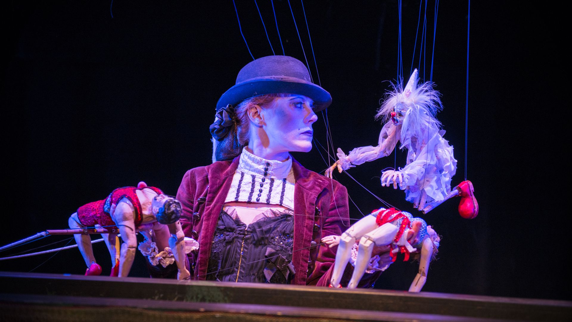 A performer in a macabre costume performs with puppets