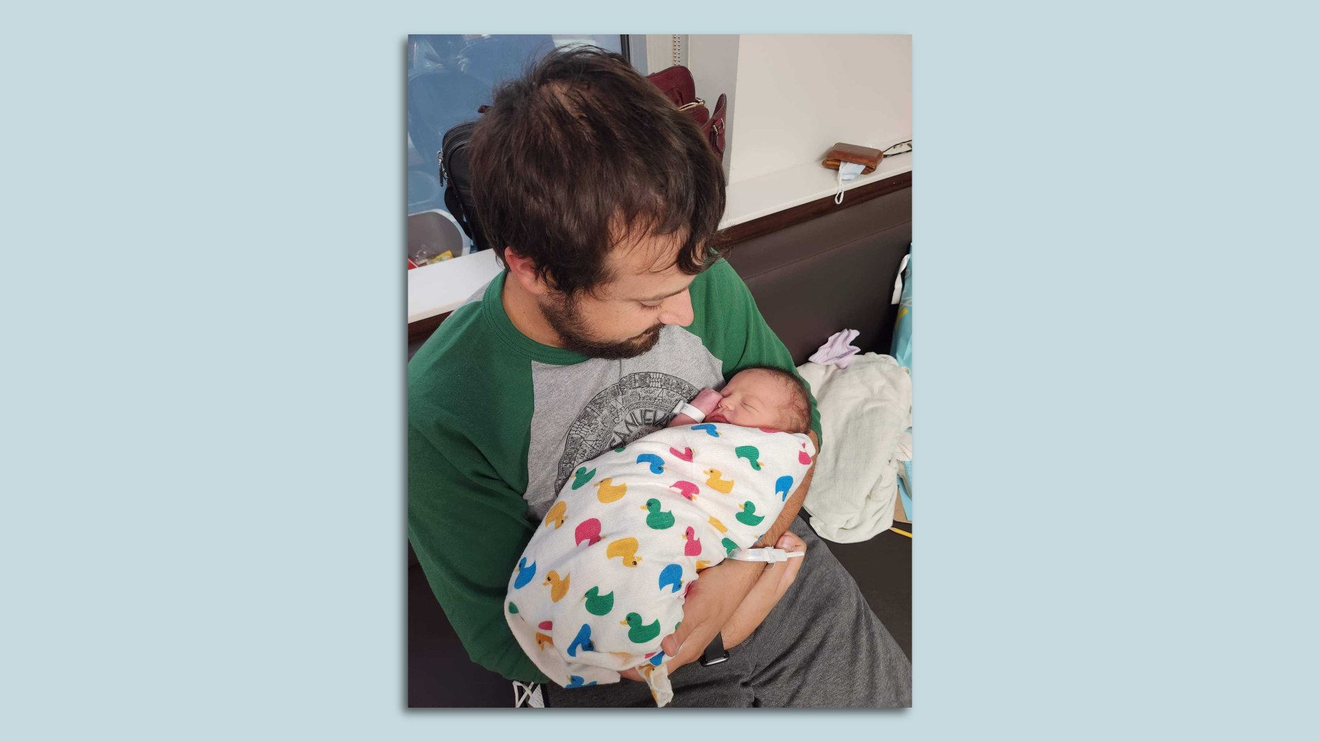 Tyler holding baby Calvin swaddled in a duck-print blanket