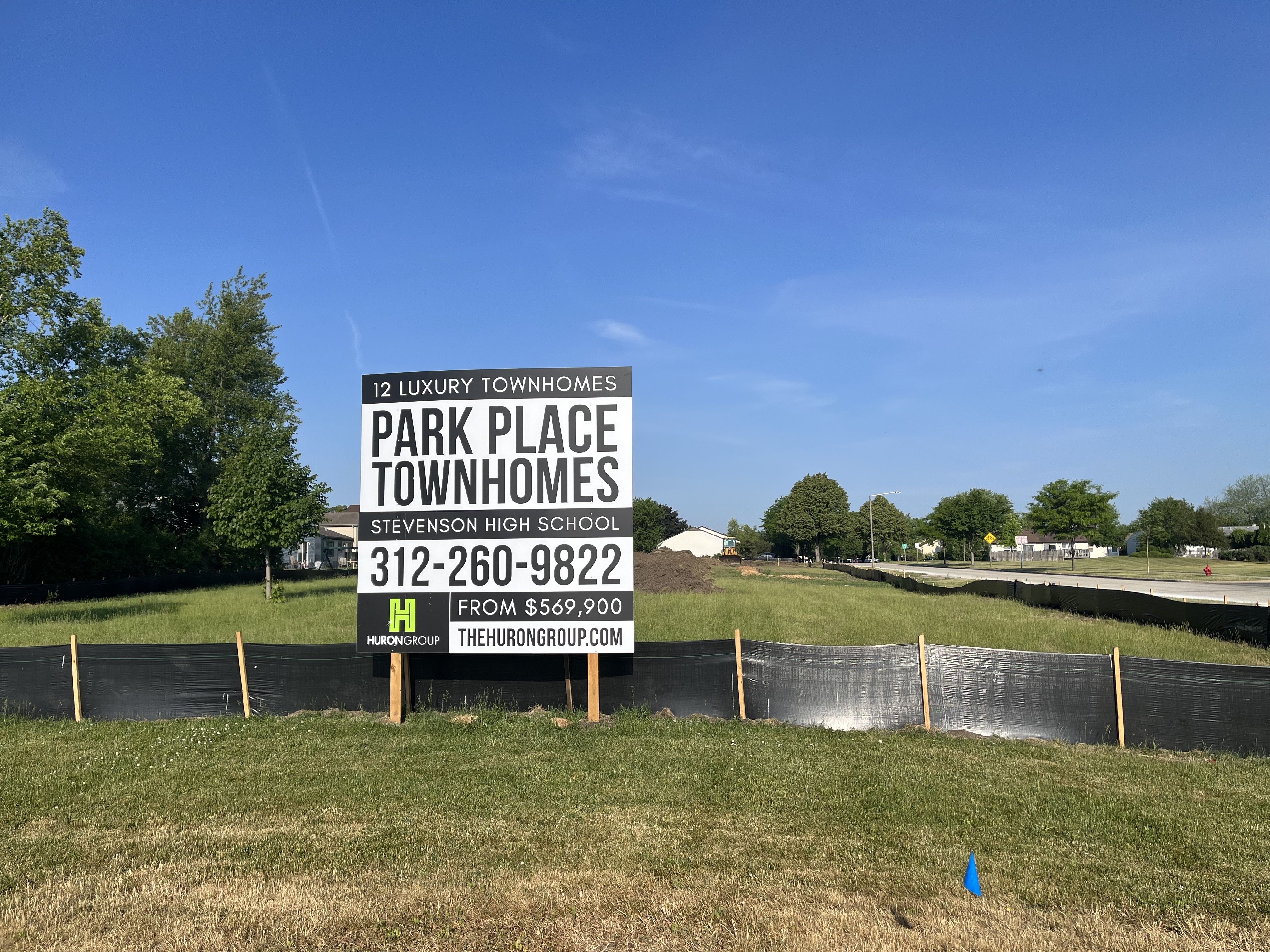 plot of land with sign reading "12 luxury townhomes" and "Stevenson High School" priced from $569,900