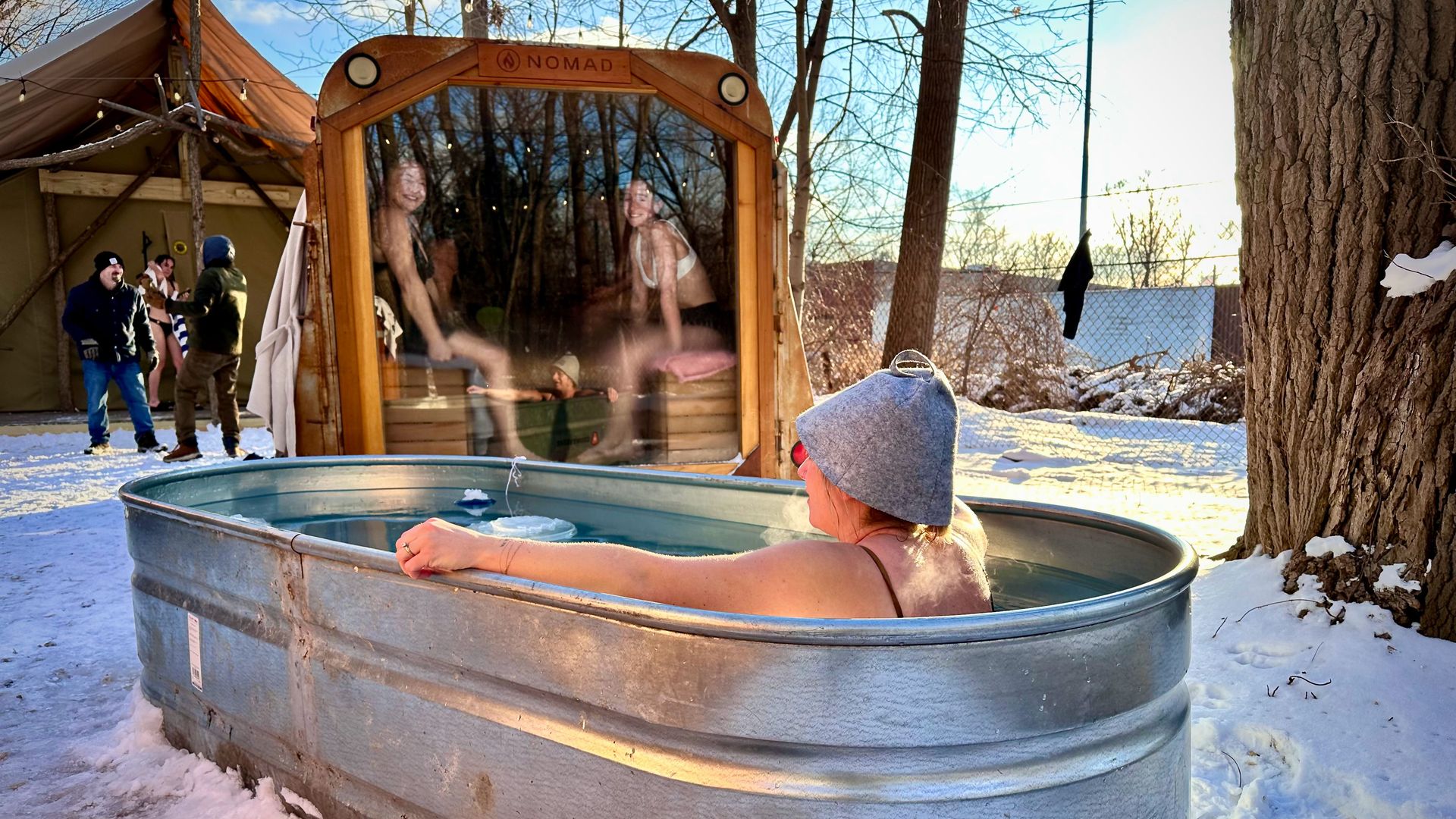 A scene at Islandview Sauna Club, with a person sitting in an outdoor cold plunge tub.