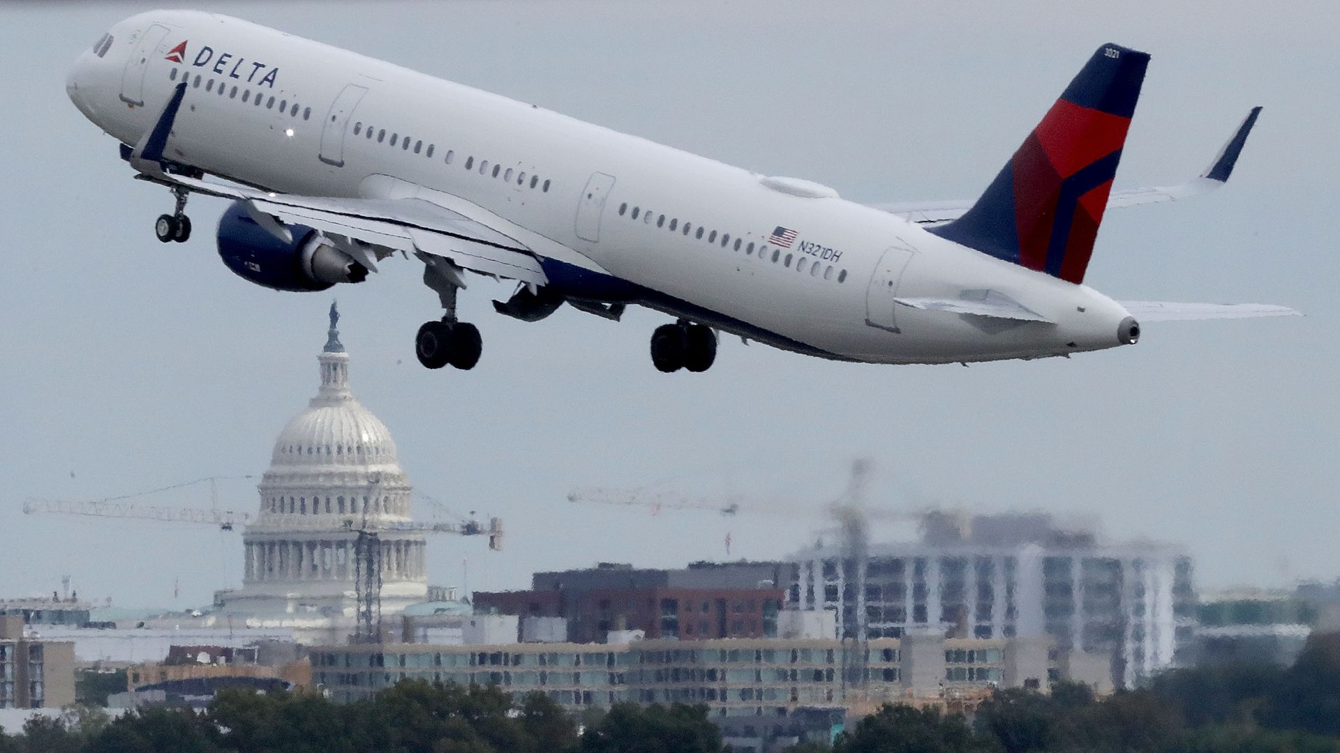 A Delta airplane takes off from DCA with the Capitol dome in the background