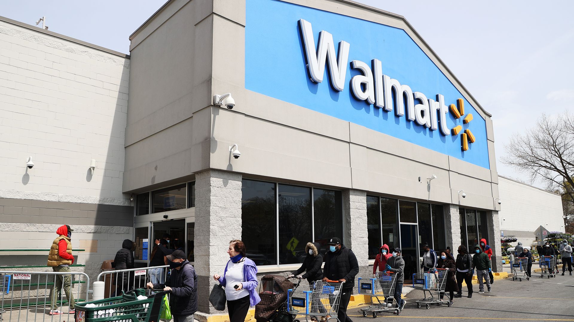 People push shopping carts in front of a Walmart store.