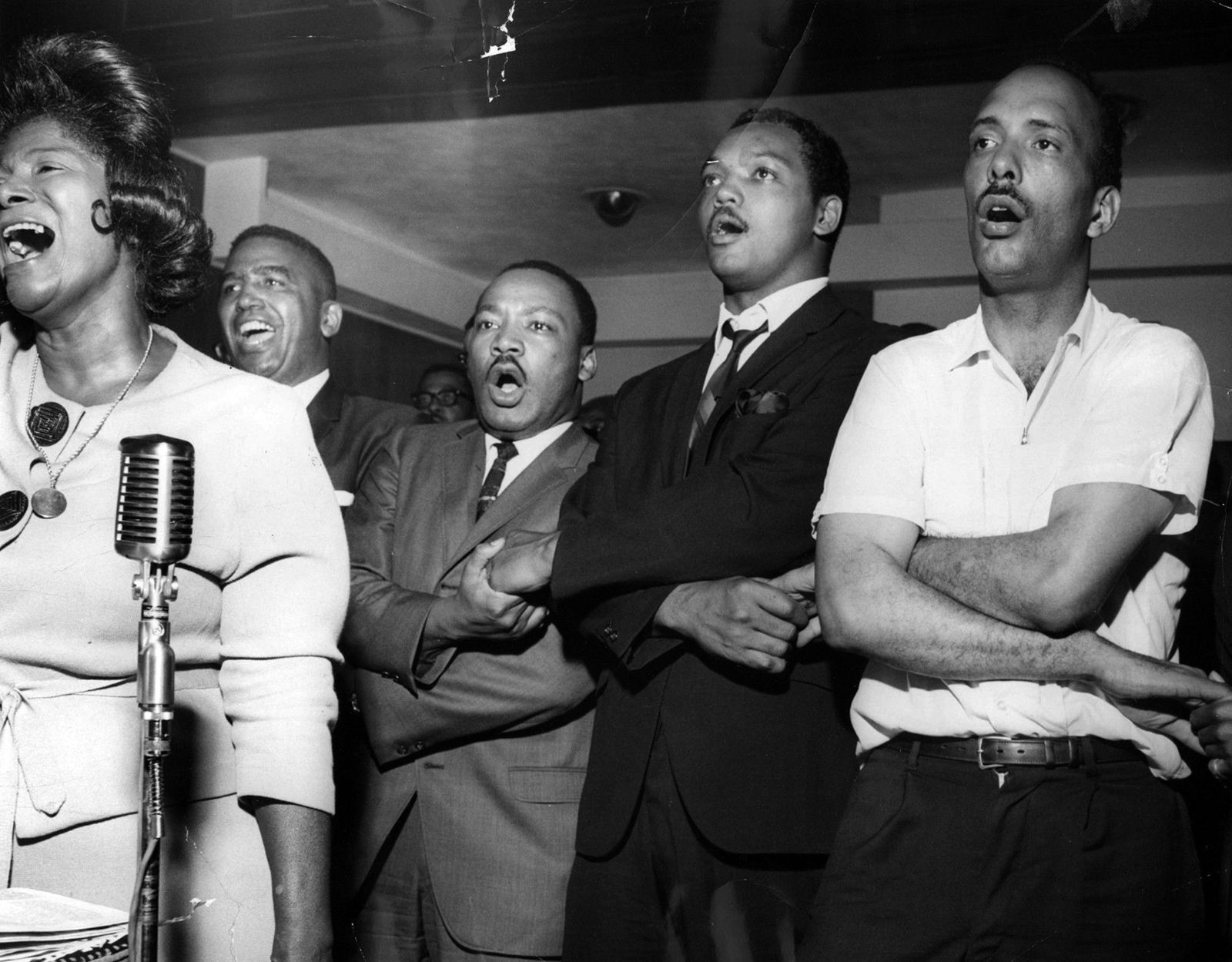 Woman singing, men holding hands, including Martin Luther King, Jr. and Jesse Jackson
