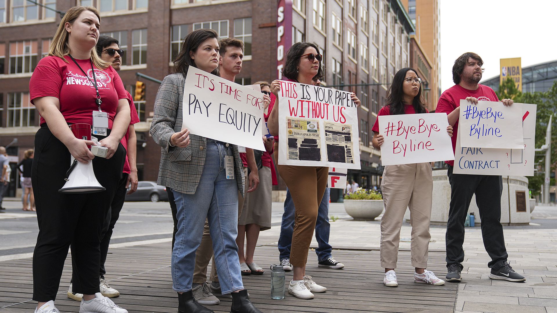 Indianapolis News Guild members picket outside, wearing red shirts and holding signs.