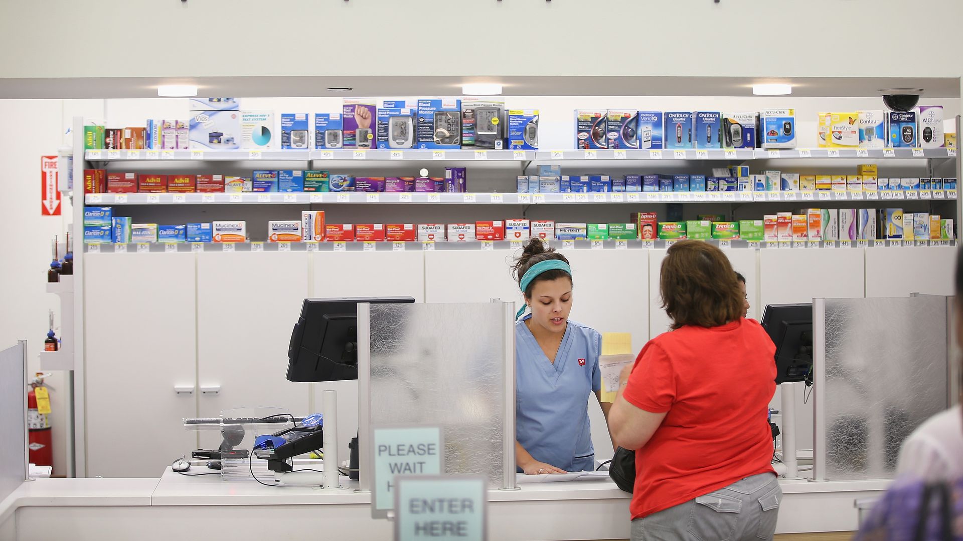 A Walgreens pharmacy technician helps a patient.
