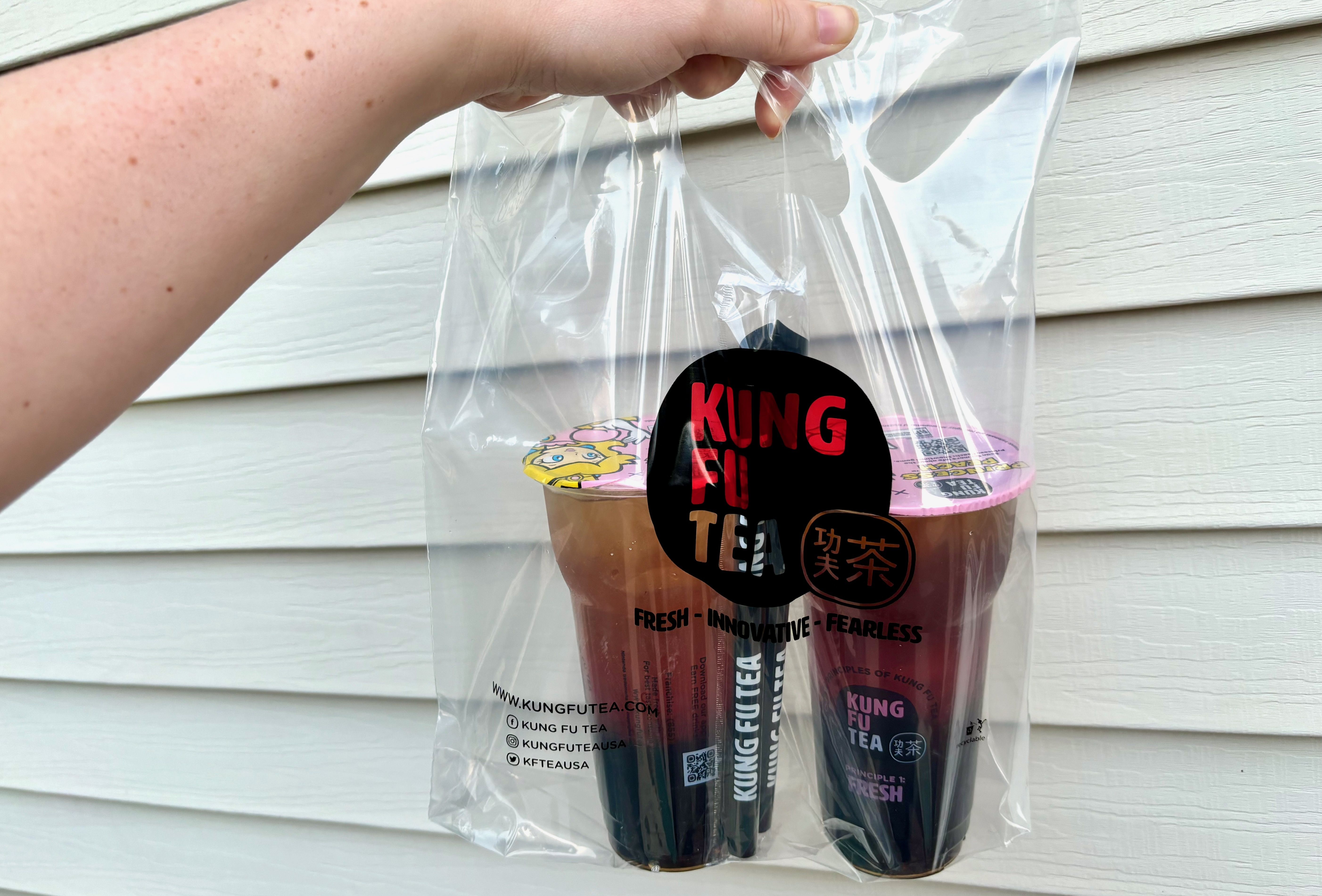A plastic bag that reads "Kung Fu Tea" with two bubble teas inside it