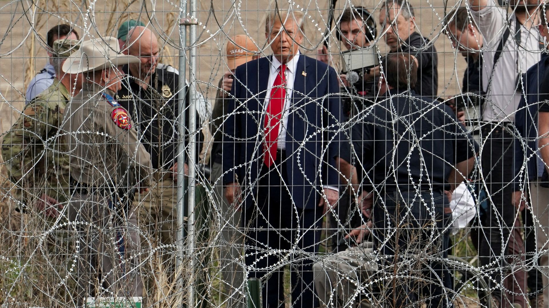 Trump is seen through barbed wire at the border in Eagle Pass, Texas, yesterday, as seen from Piedras Negras, Mexico