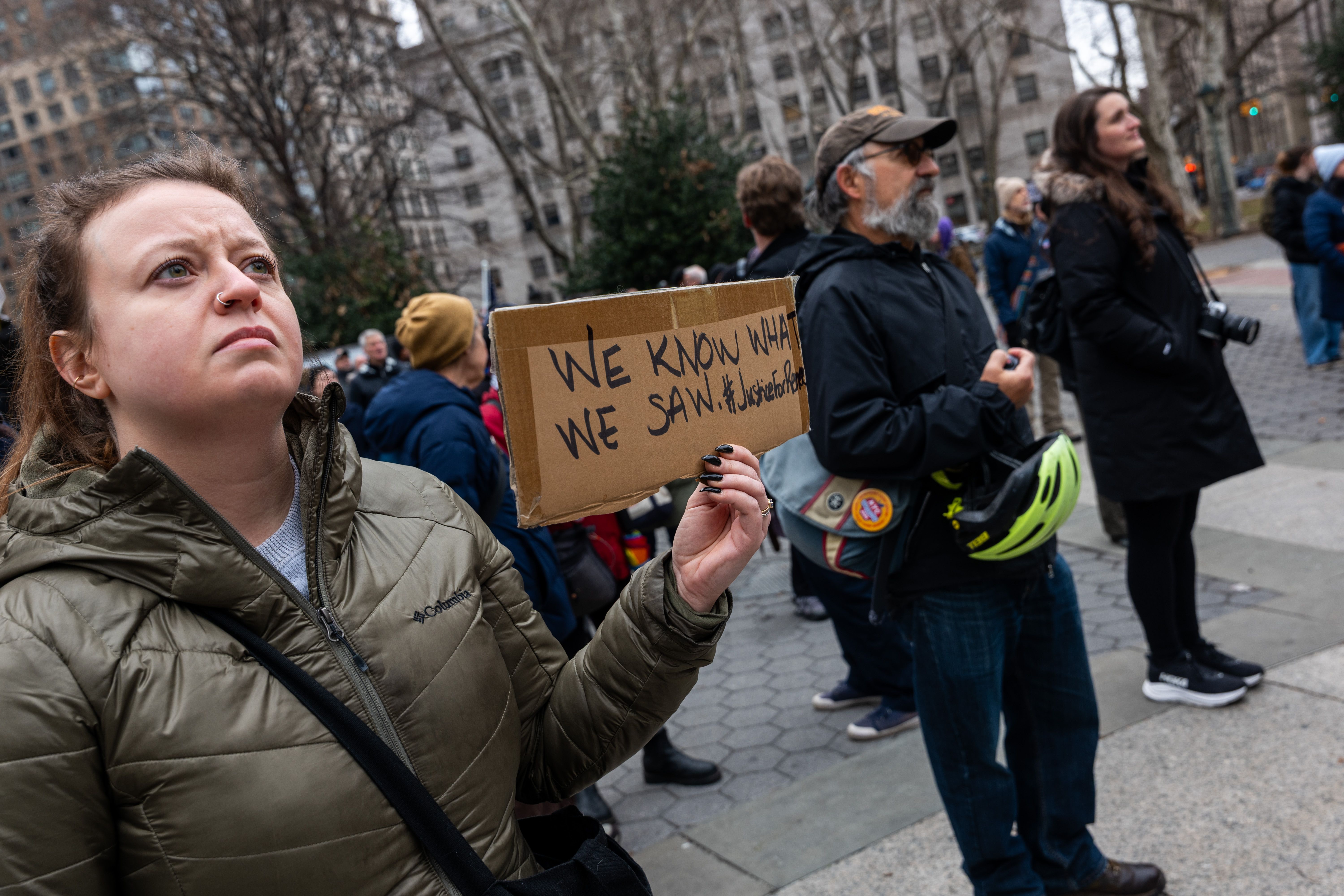 A woman holds a sign reading “We know what we saw.”