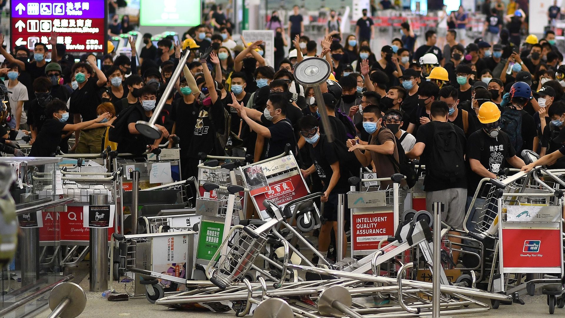 protestors create a barricade of luggage carts at the airport