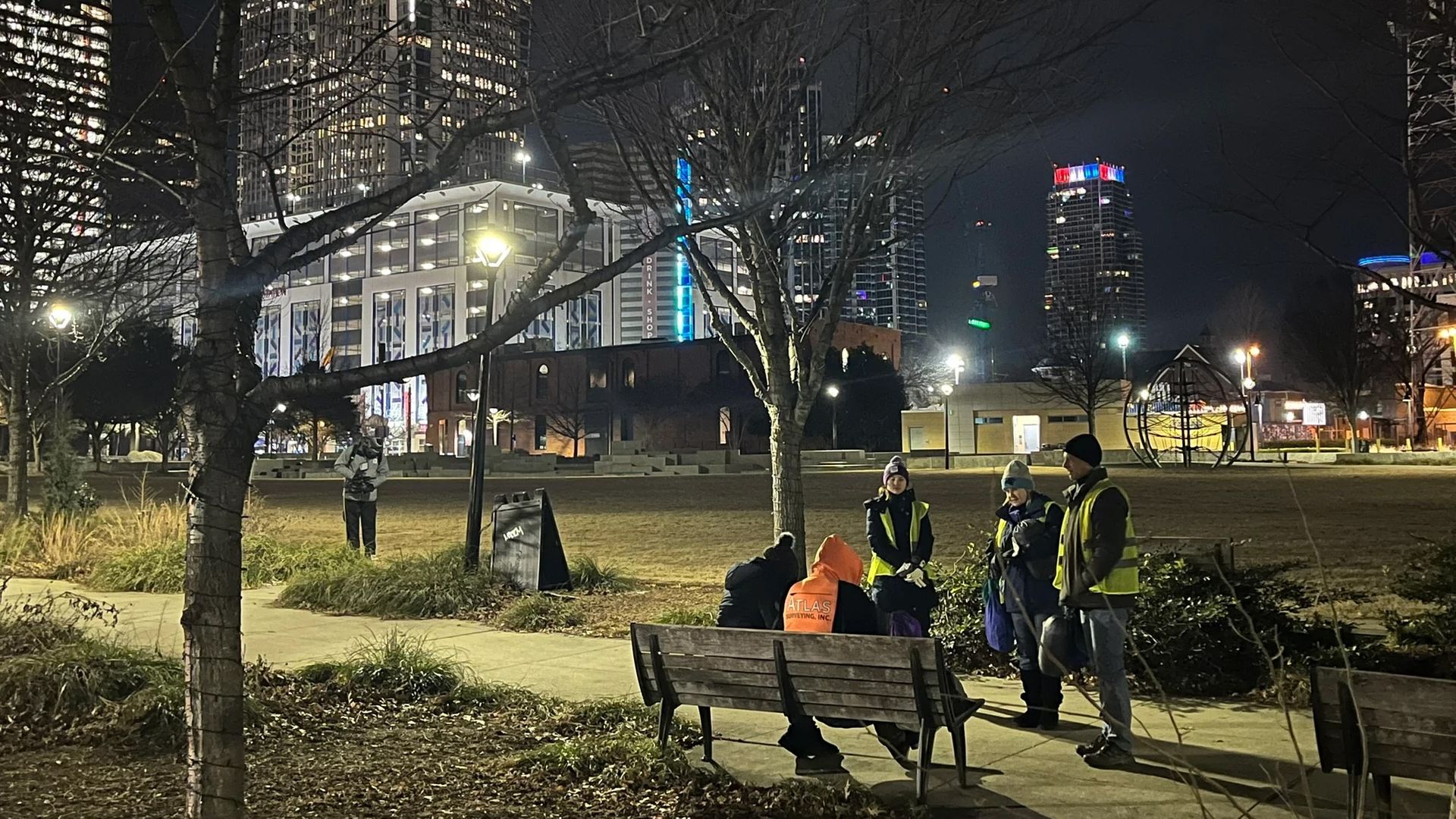 Volunteers talk to people sitting on a bench at night