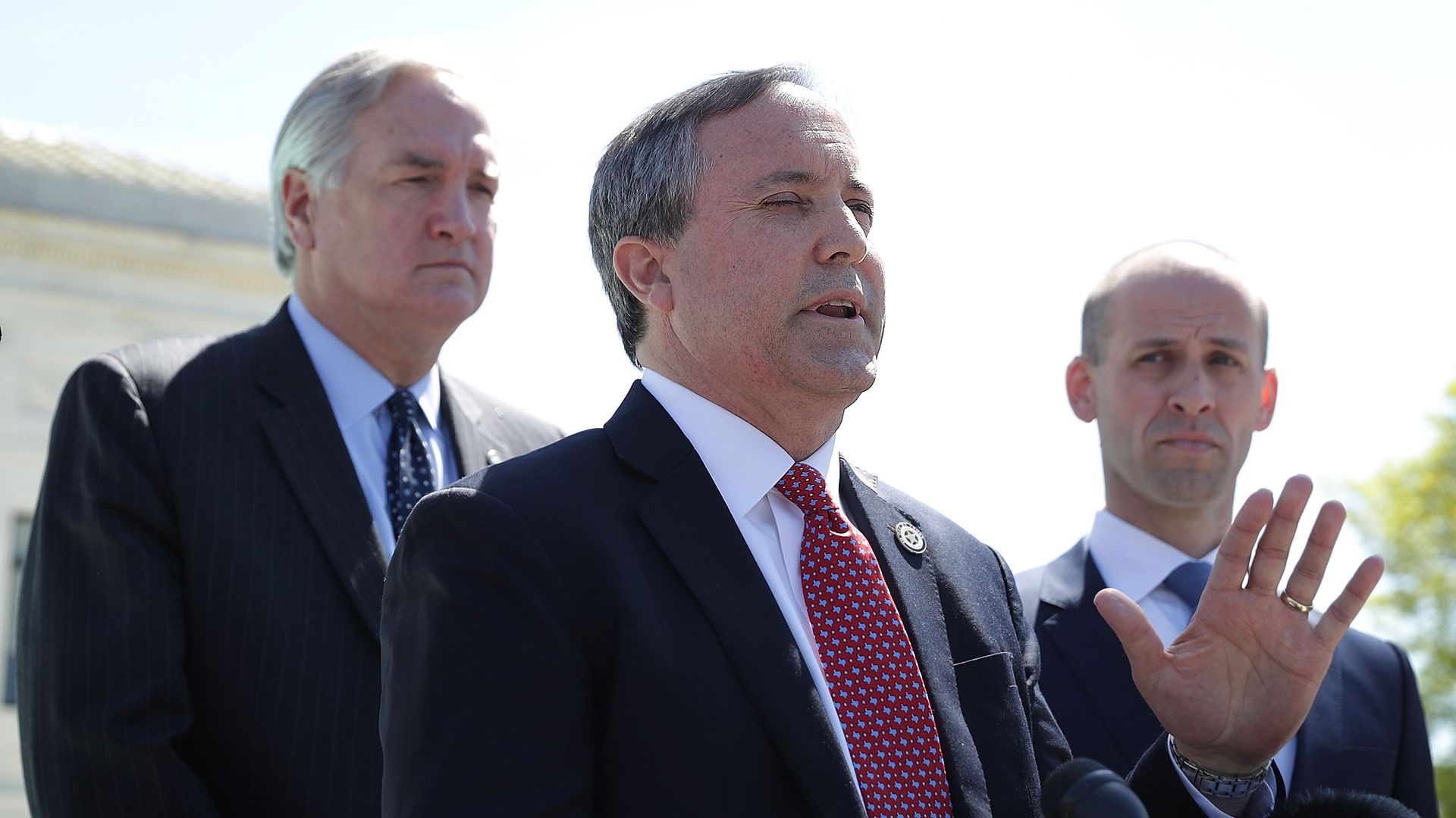 Texas AG Ken Paxton speaking outside at a podium