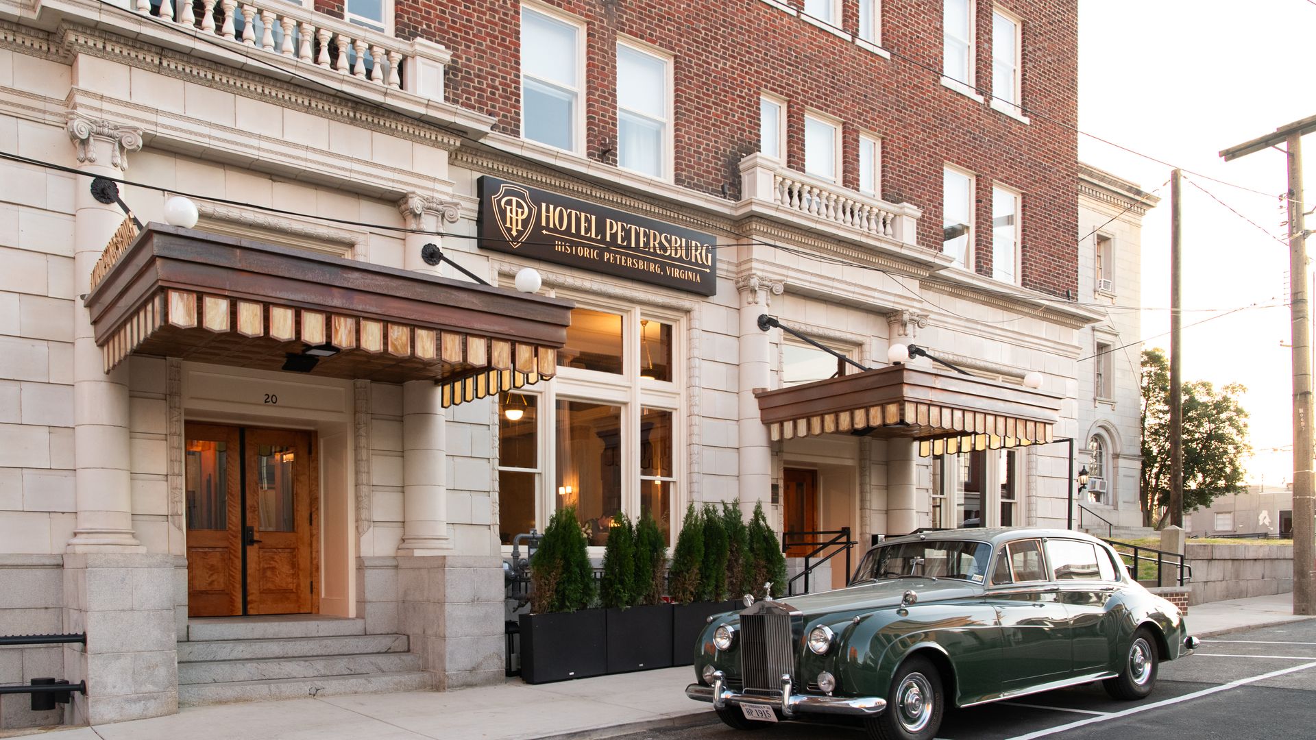 A vintage 1930s car in front of a 1919 hotel building
