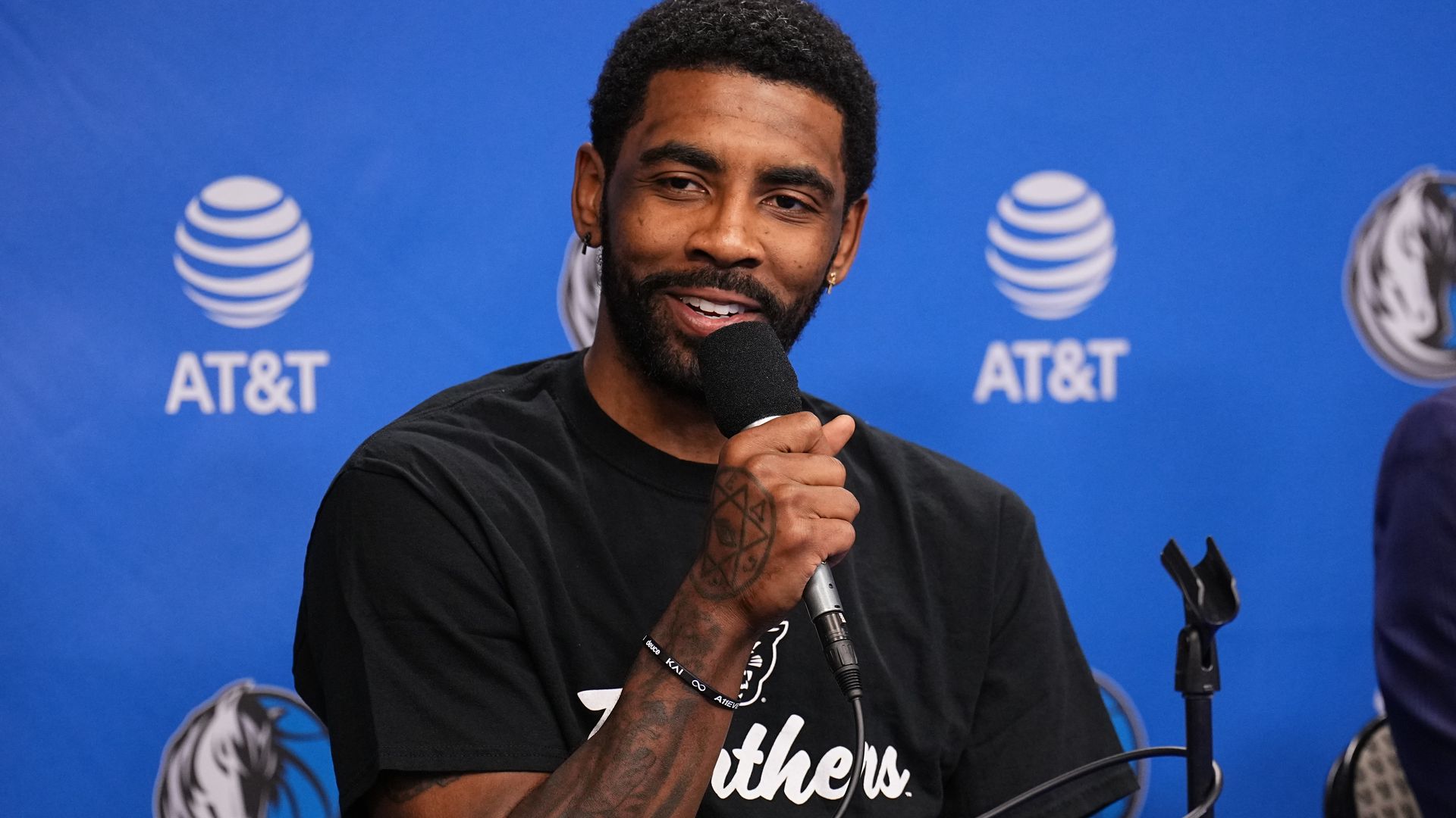 Kyrie Irving holds a microphone at a press conference