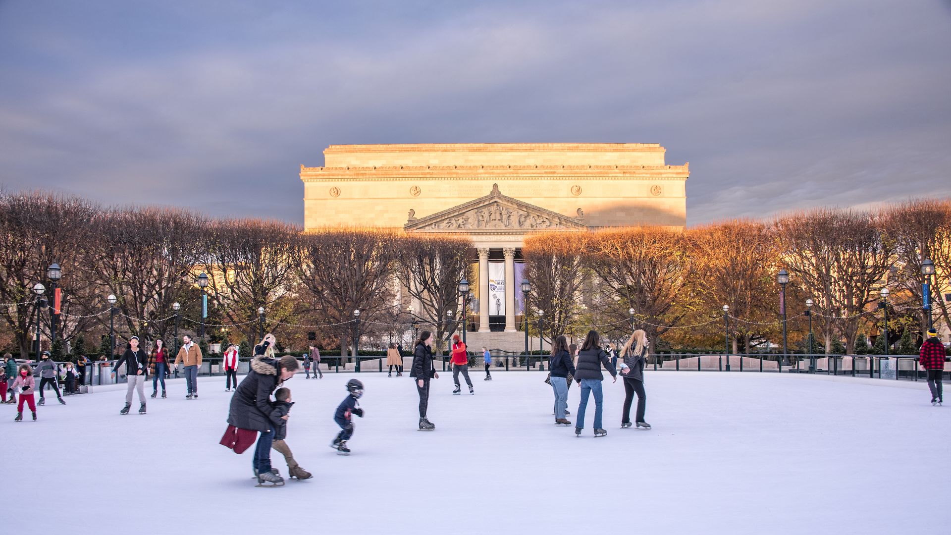 The ice rink outside the National Gallery of Art with skaters surrounded by trees