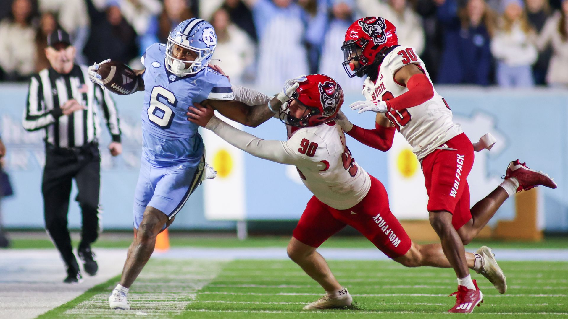 CHAPEL HILL, NC - NOVEMBER 30: North Carolina Tar Heels wide receiver Nate McCollum (6) stiff arms North Carolina State Wolfpack place kicker Collin Smith (90) during the college basketball game between the North Carolina Tar Heels and the North Carolina State Wolfpack on November 30, 2024 at Kenan 