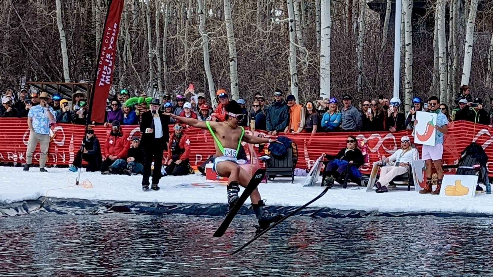 A man in suspenders ski-jumps into a pond.