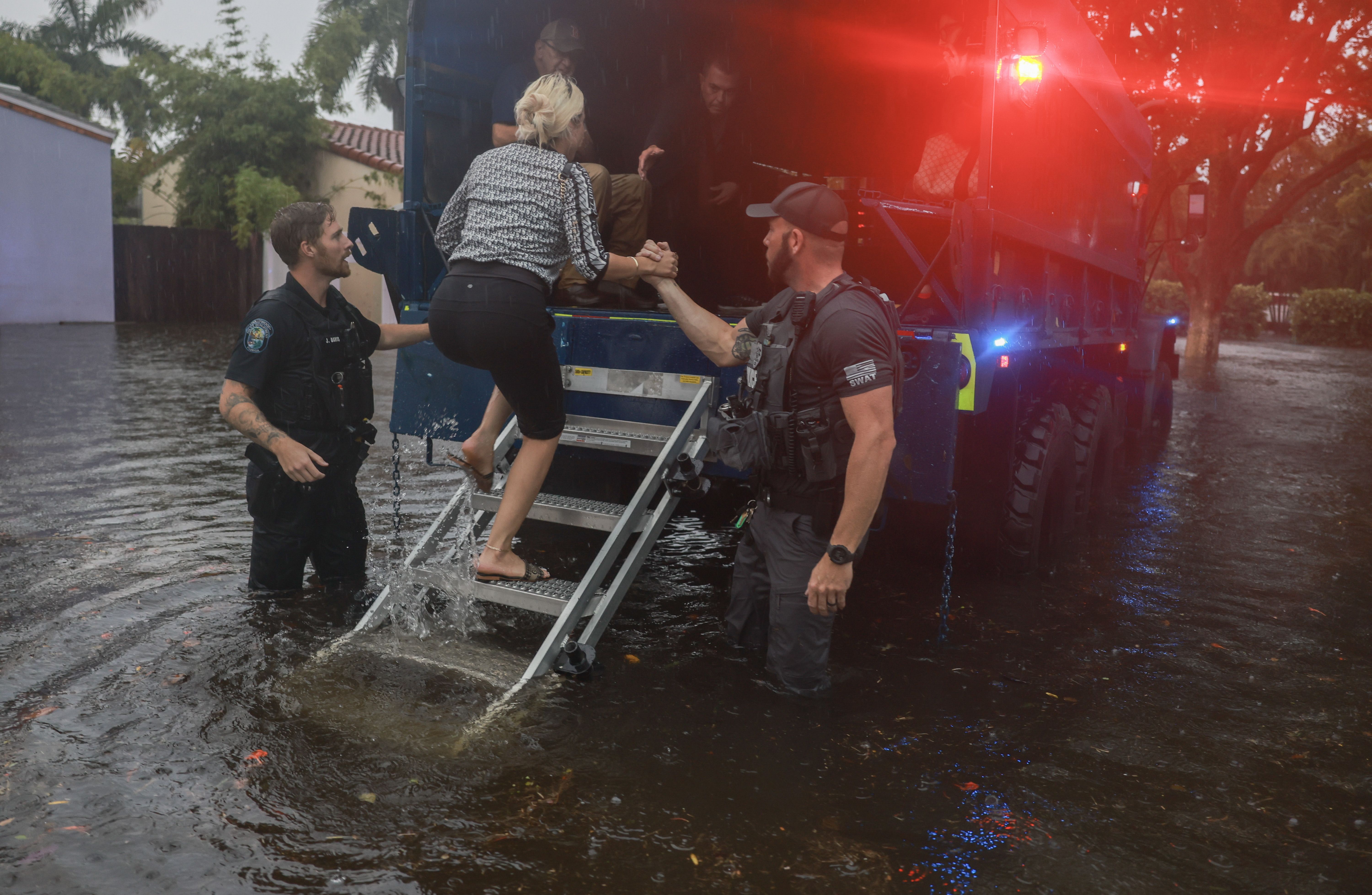 A City of Hollywood SWAT team member helps a person into a City of Hollywood search and rescue truck as people are evacuated from a flooded area on June 12, 2024, in Hollywood, Florida. 