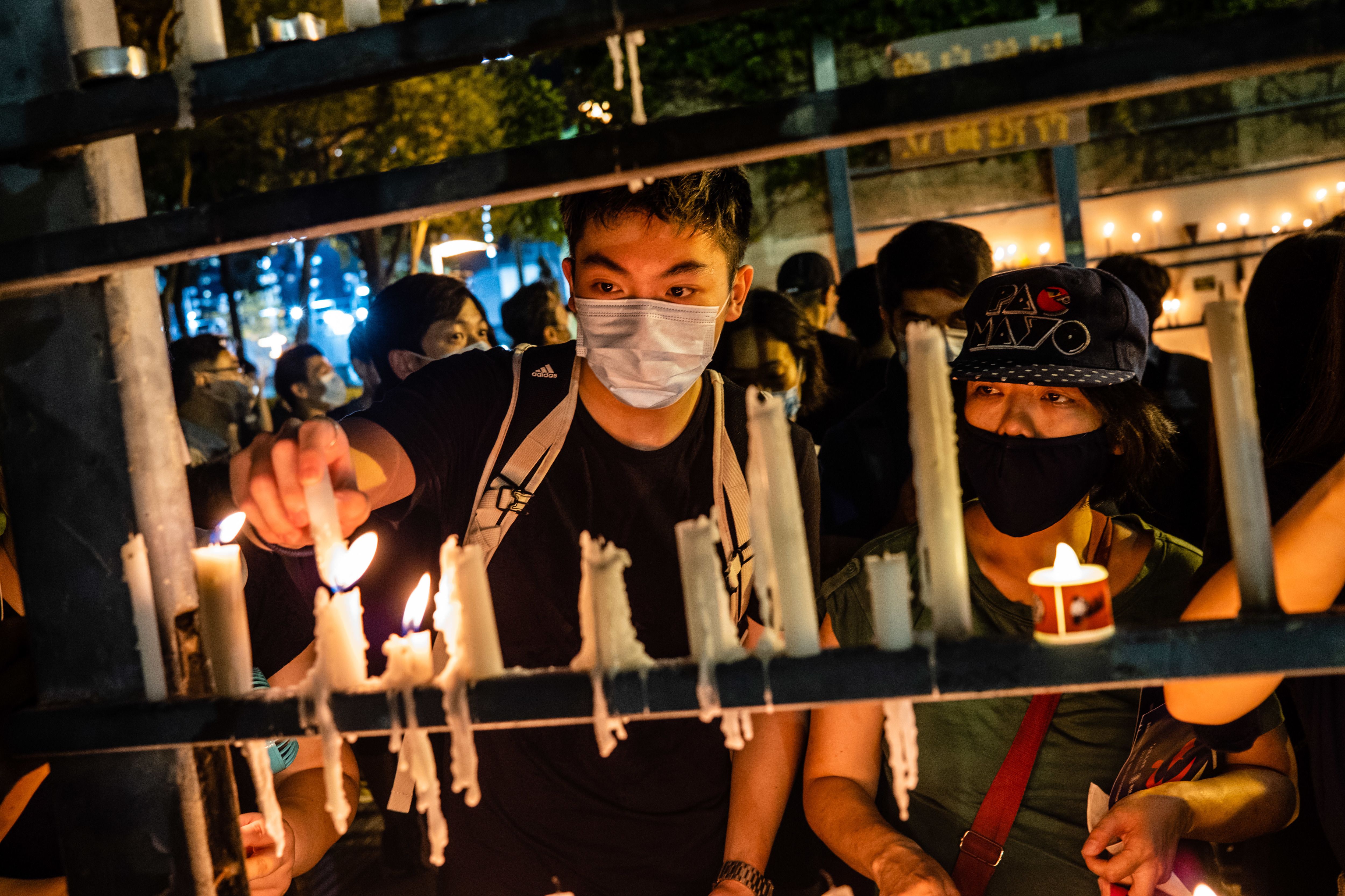 In this image, a man wearing a face mask lights candles 