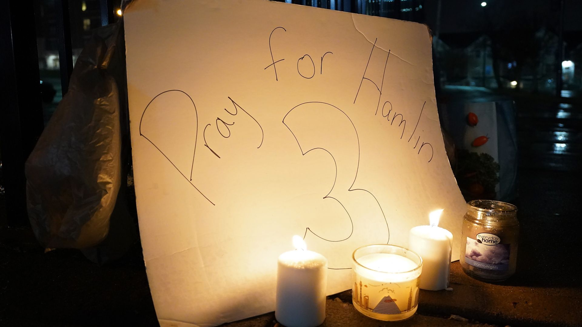 Candles and a sign that says "pray for Hamlin" and the number three. 