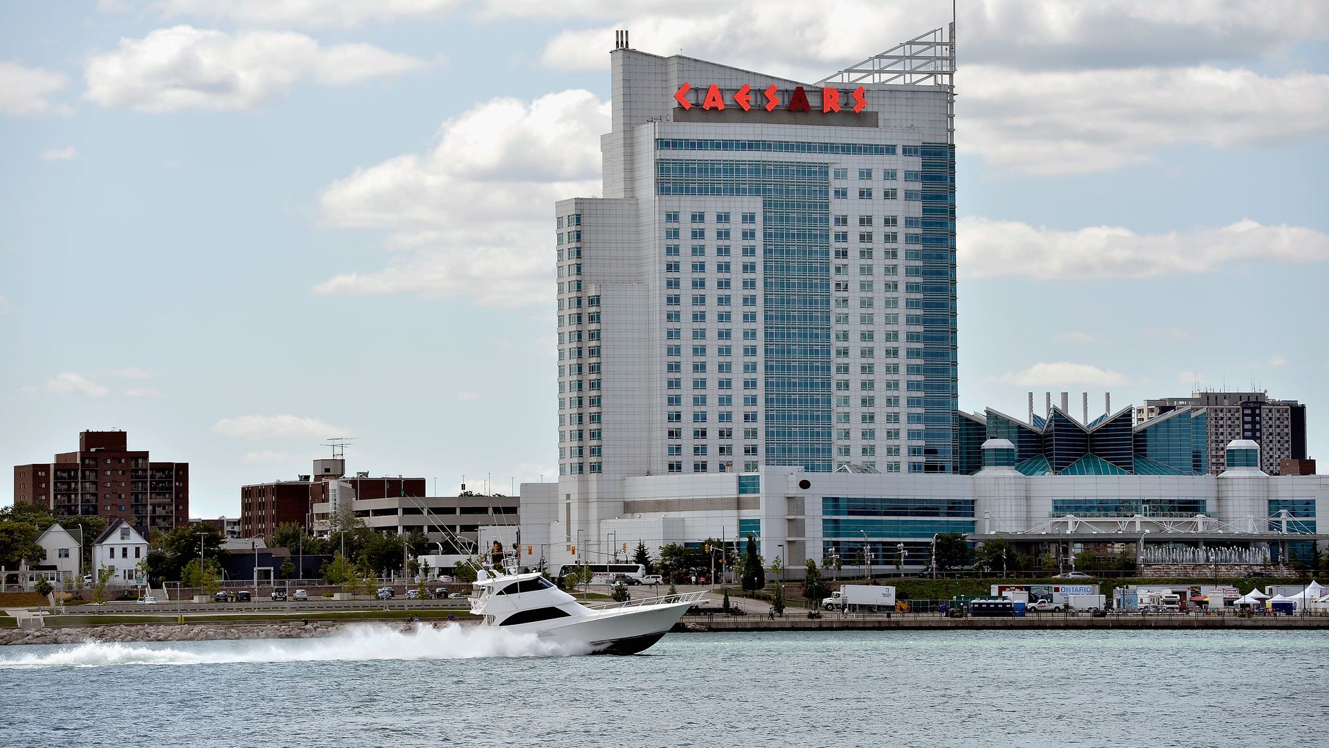 A boat cruises on the Detroit River with Windsor in the background.