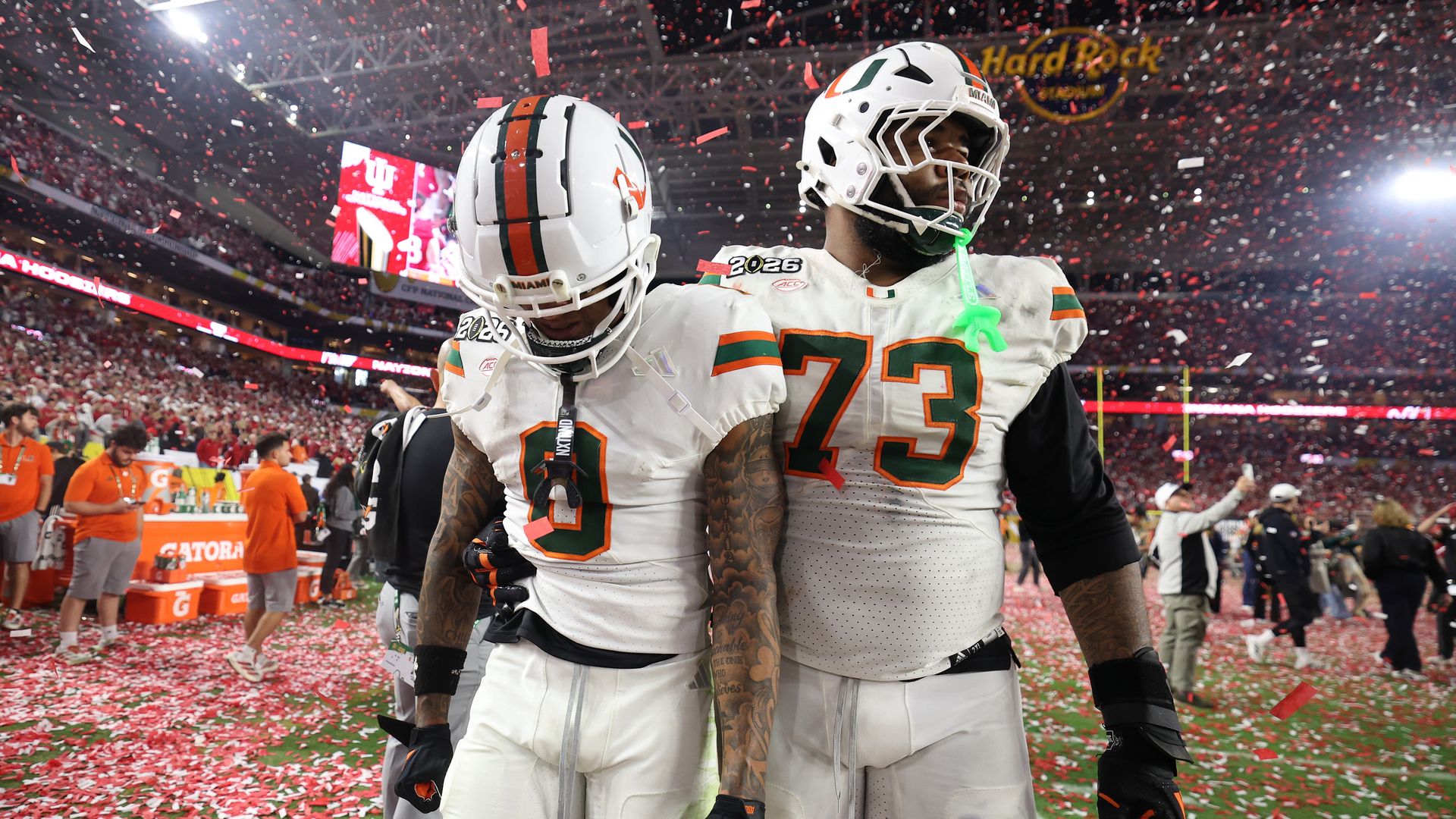 Two UM football players surrounded by confetti while looking somber. 