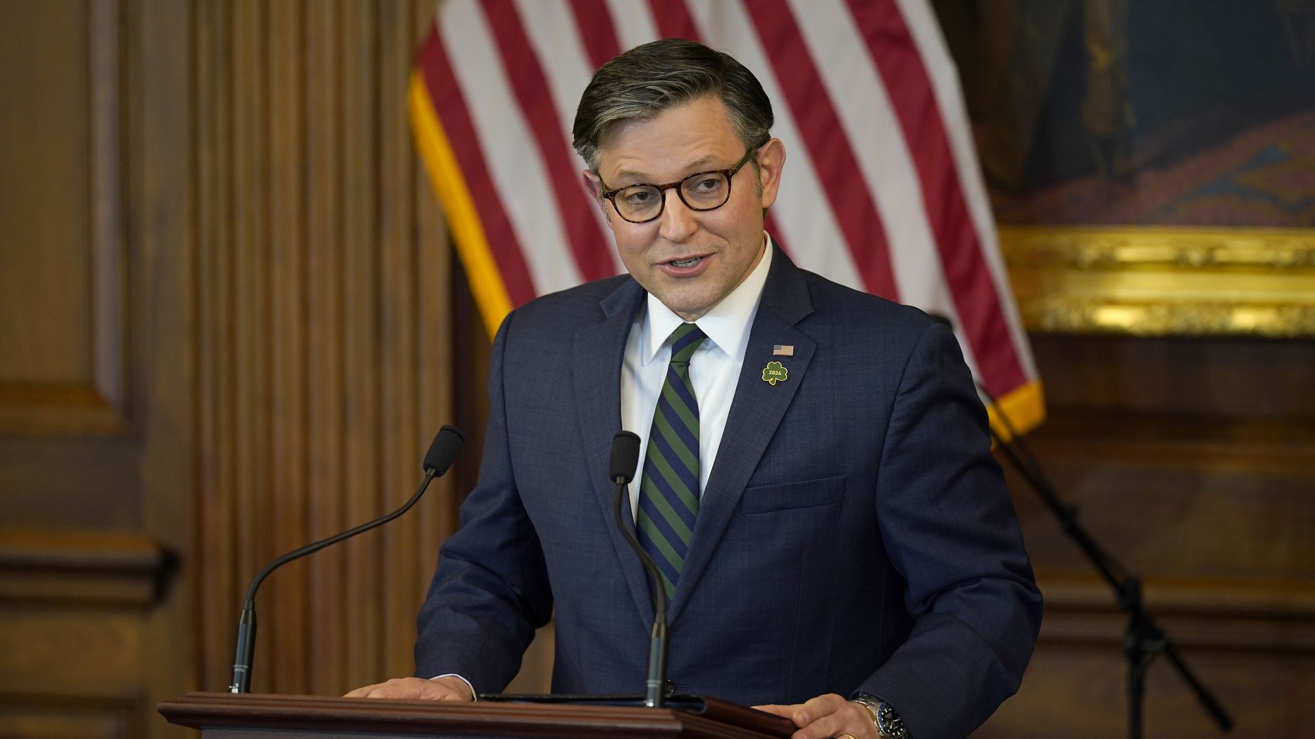House Speaker Mike Johnson, wearing a dark blue suit, white shirt and blue and green striped tie.